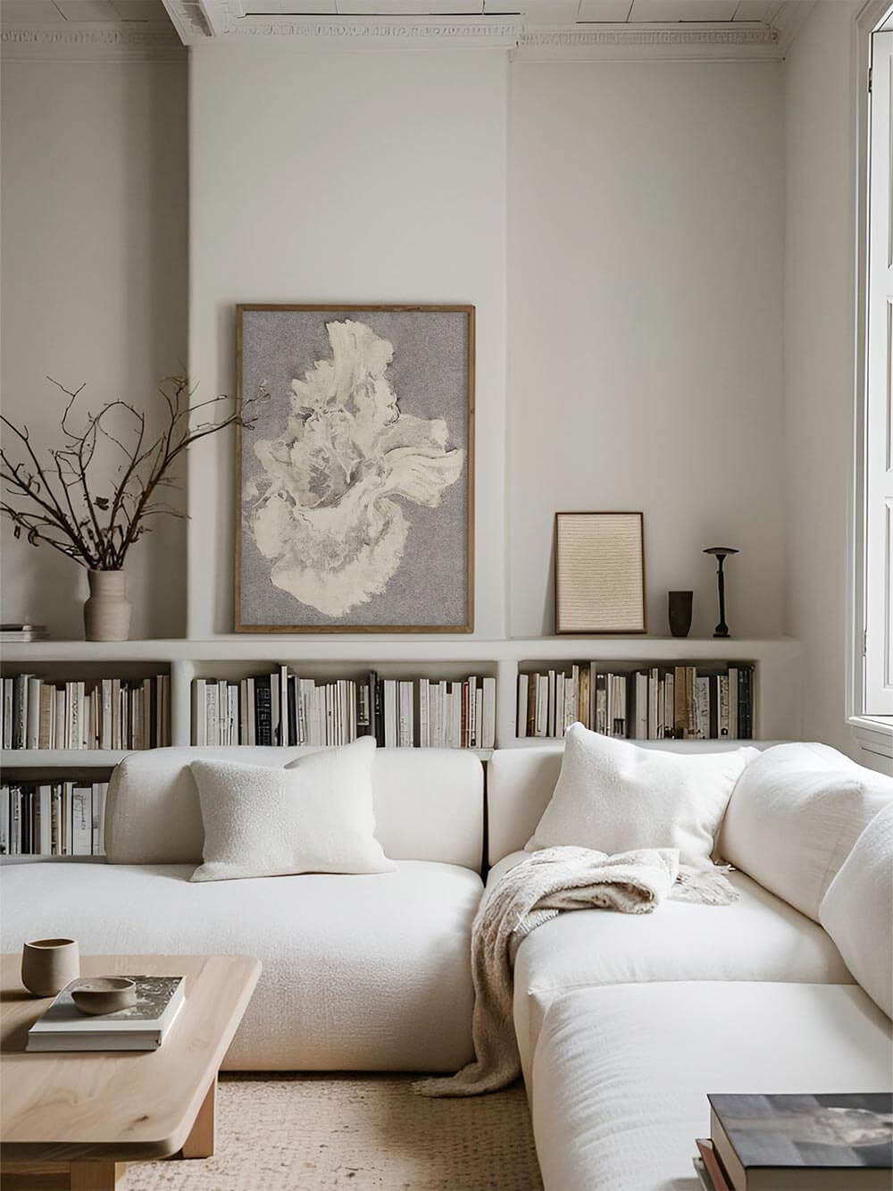 Der großformatige Wabi-Sabi Kunstdruck hängt über einem hellen Bücherregal. Die dezente Farbpalette ergänzt das zurückhaltend gestaltete Wohnzimmer harmonisch.