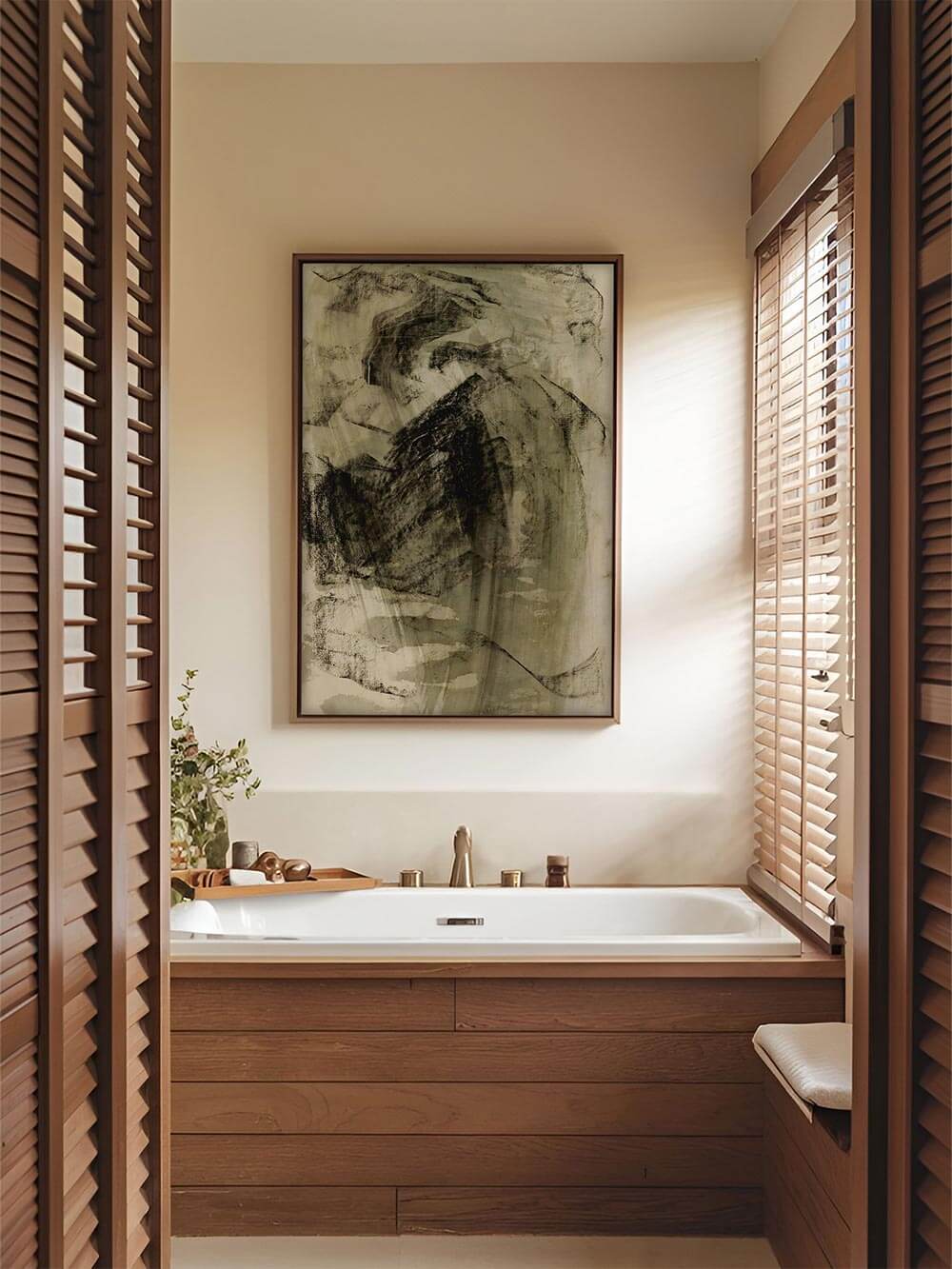 Ein abstrakter Kunstdruck im Wabi-Sabi-Stil ziert die Wand über einer hellen Badewanne. Die raue Textur des Bildes setzt einen ruhigen, meditativen Akzent im Raum.