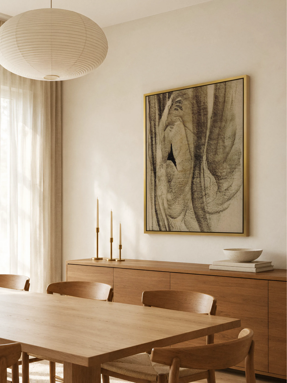 Abstraktes Leinwandbild im Goldrahmen über einem Sideboard aus warmem Holz mit Messingkerzenhaltern, davor ein Esstisch mit Holzstühlen und eine Papierleuchte. Das Wabi Sabi Wandbild passt zu den warmen Holztönen.