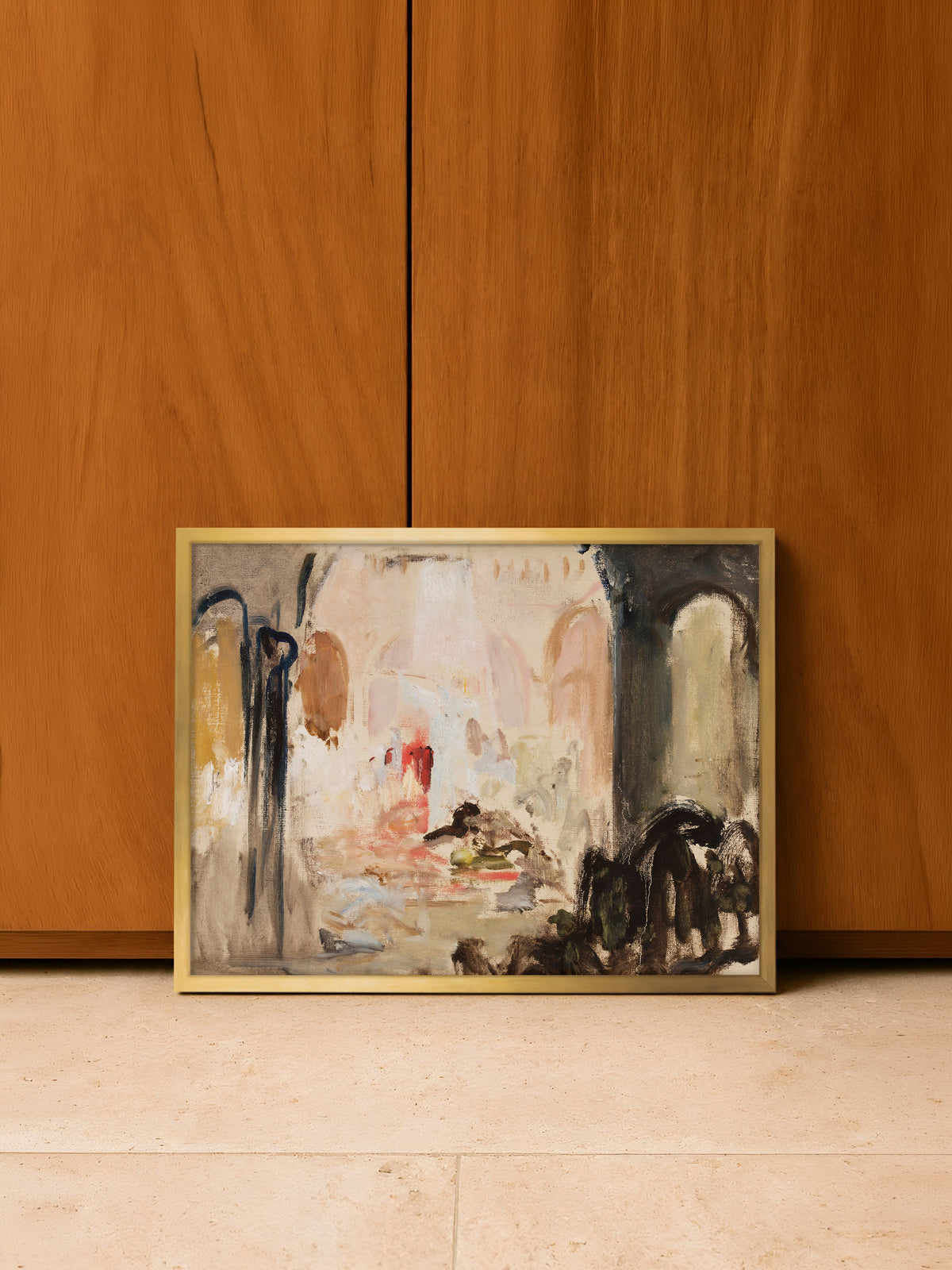Abstrakter Kunstdruck im goldenen Rahmen, angelehnt auf einem hellen Steinboden vor warm schimmernden Schranktüren aus Holz. Die Rosé- und Ockertöne des Vintage-Posters greifen die Farbe des Holzes auf.