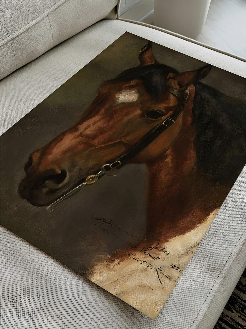 Kunstdruck mit Pferdeporträt liegt leicht gewölbt auf hellem Sofa und zeigt die vollständige Komposition, matte Oberfläche und warme Farbwirkung, passend für klassische Wandbilder und hochwertige Interior-Konzepte.