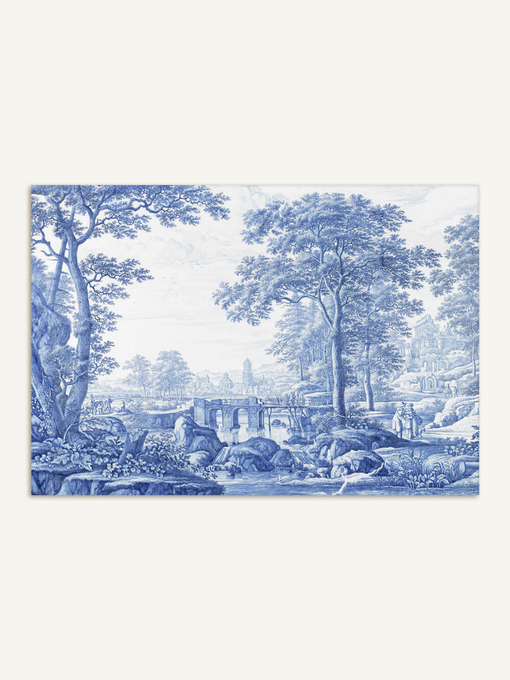 Ein eleganter Chinoiserie-Wanddruck in Blautönen zeigt eine idyllische Landschaft mit großen, detailliert gezeichneten Bäumen, einer Steinbrücke über einen ruhigen Fluss und mehreren Figuren, die in der Ferne spazieren. Im Hintergrund sind historische Gebäude und Türme zu erkennen, was der Szene eine nostalgische, klassische Atmosphäre verleiht.
