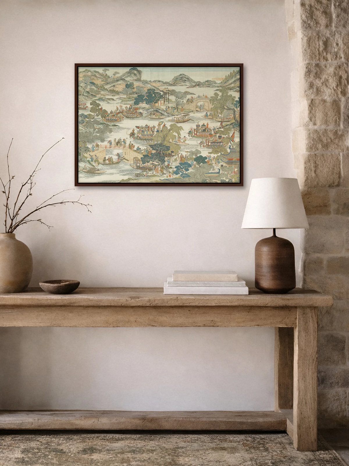 Chinoiserie Landschaft als Leinwandbild im braunen Rahmen über einer rustikalen Holzkonsole im Flur. Darauf stehen eine Tonvase mit Zweigen, eine Holzschale, Bücher und eine Lampe mit Keramikfuß, daneben eine Natursteinwand.