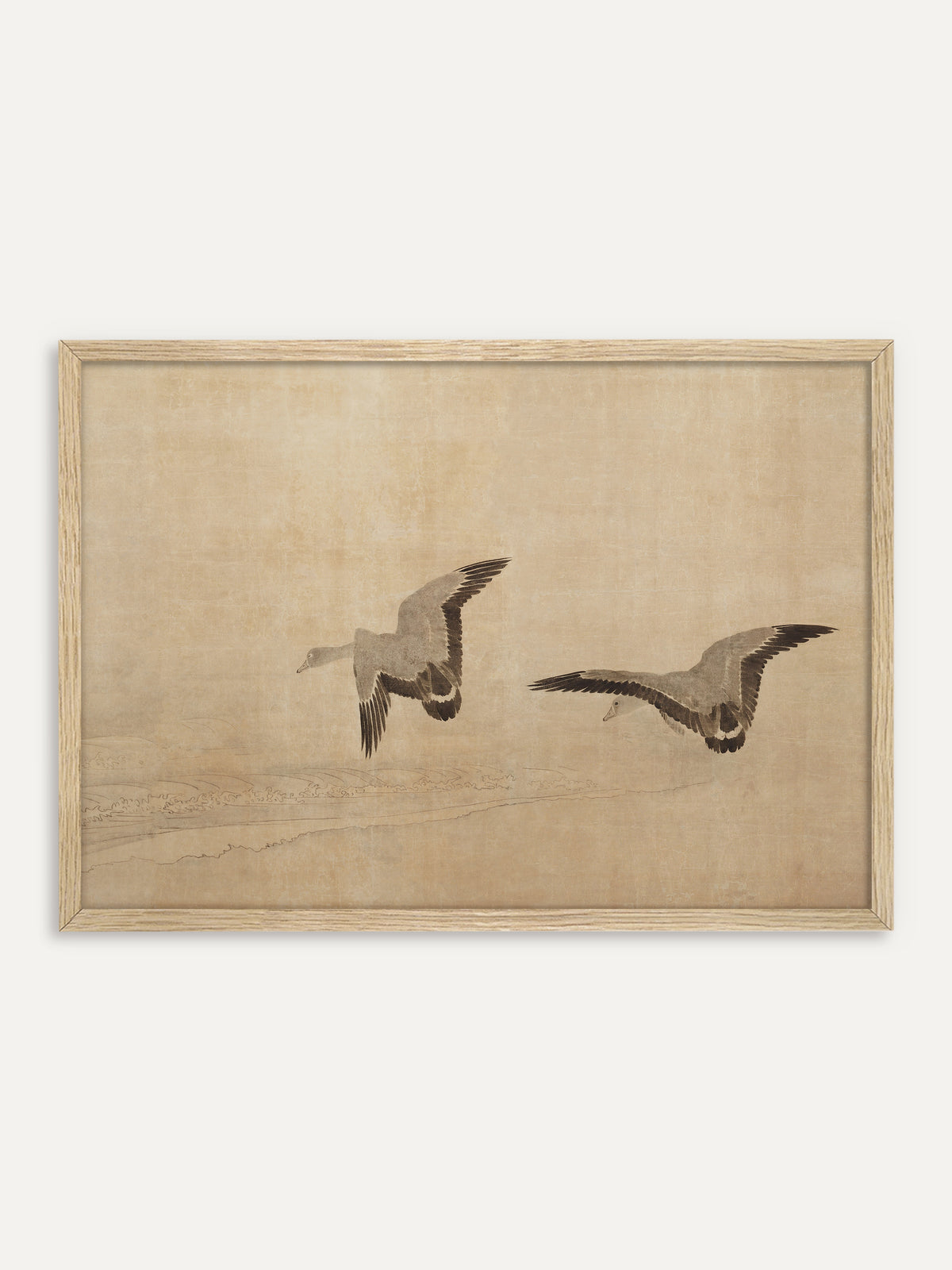 Kunstdruck, der zwei Gänse mit ausgebreiteten Schwingen in Grau und Braunschwarz zeigt, die über feine Wellenlinien an einem Strand fliegen, auf warmem, sandfarbenem Grund. Im Rahmen aus hellem Holz wirkt das stille Motiv luftig und passt zu einer Einrichtung im Japandi-Stil. #Rahmen_Helles Holz