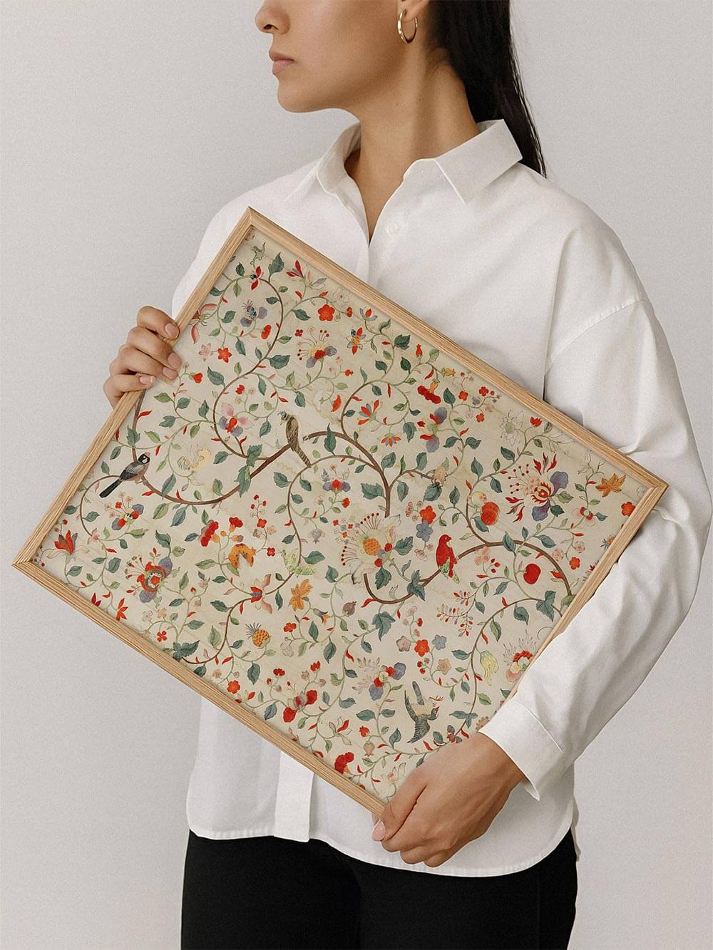 Chinoiserie Kunstdruck mit floralem Muster wird von einer Person im hellen Holzrahmen gehalten. Die zarten Farben und feinen Details wirken beruhigend und zeitlos.