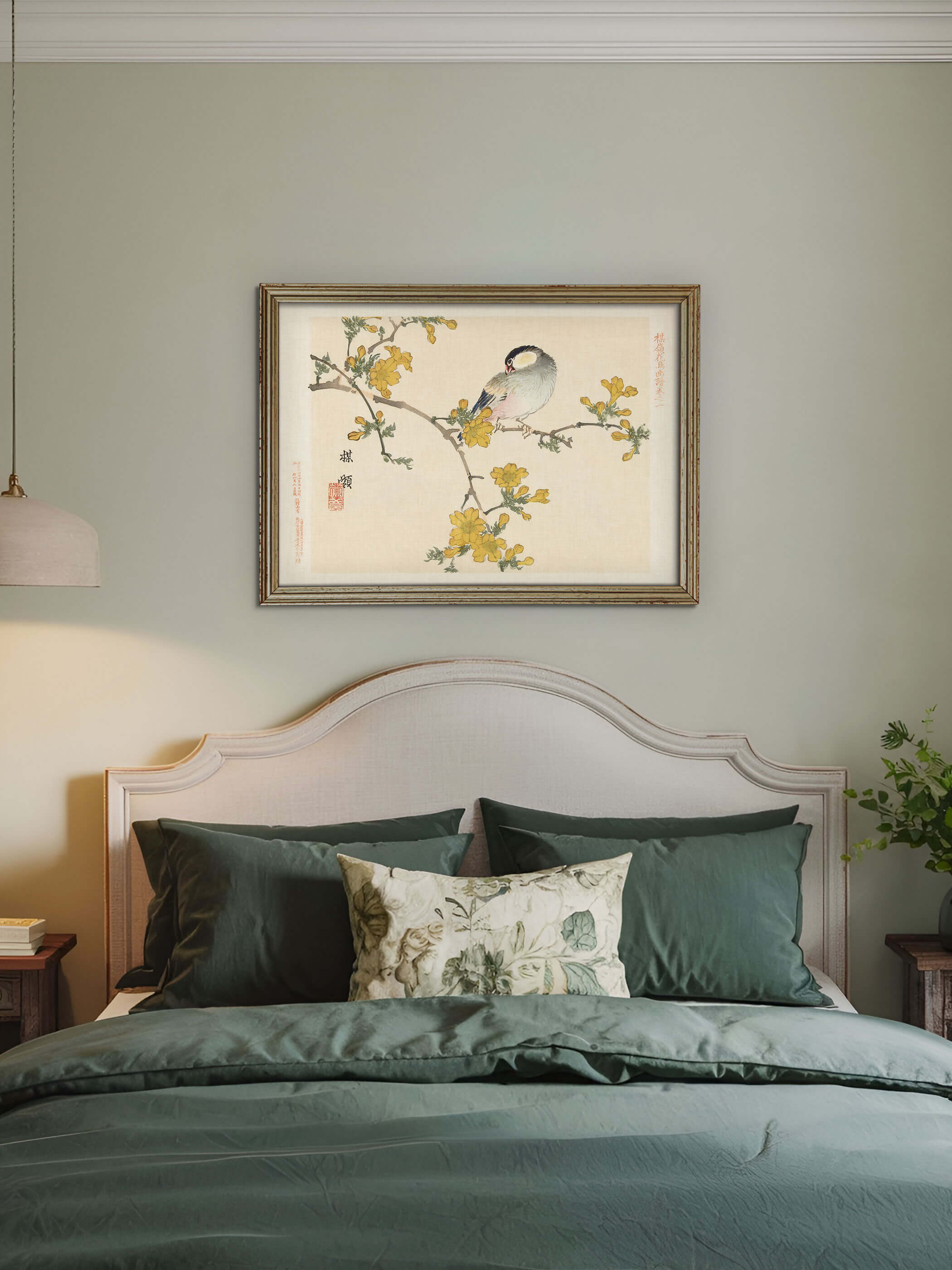 Gerahmter Chinoiserie Kunstdruck mit Reisvogel und gelben Blüten hängt über einem Bett mit dunkelgrüner Bettwäsche vor salbeigrüner Wand. Das vintage Wandbild bringt eine ruhige, naturverbundene Stimmung ins Schlafzimmer.