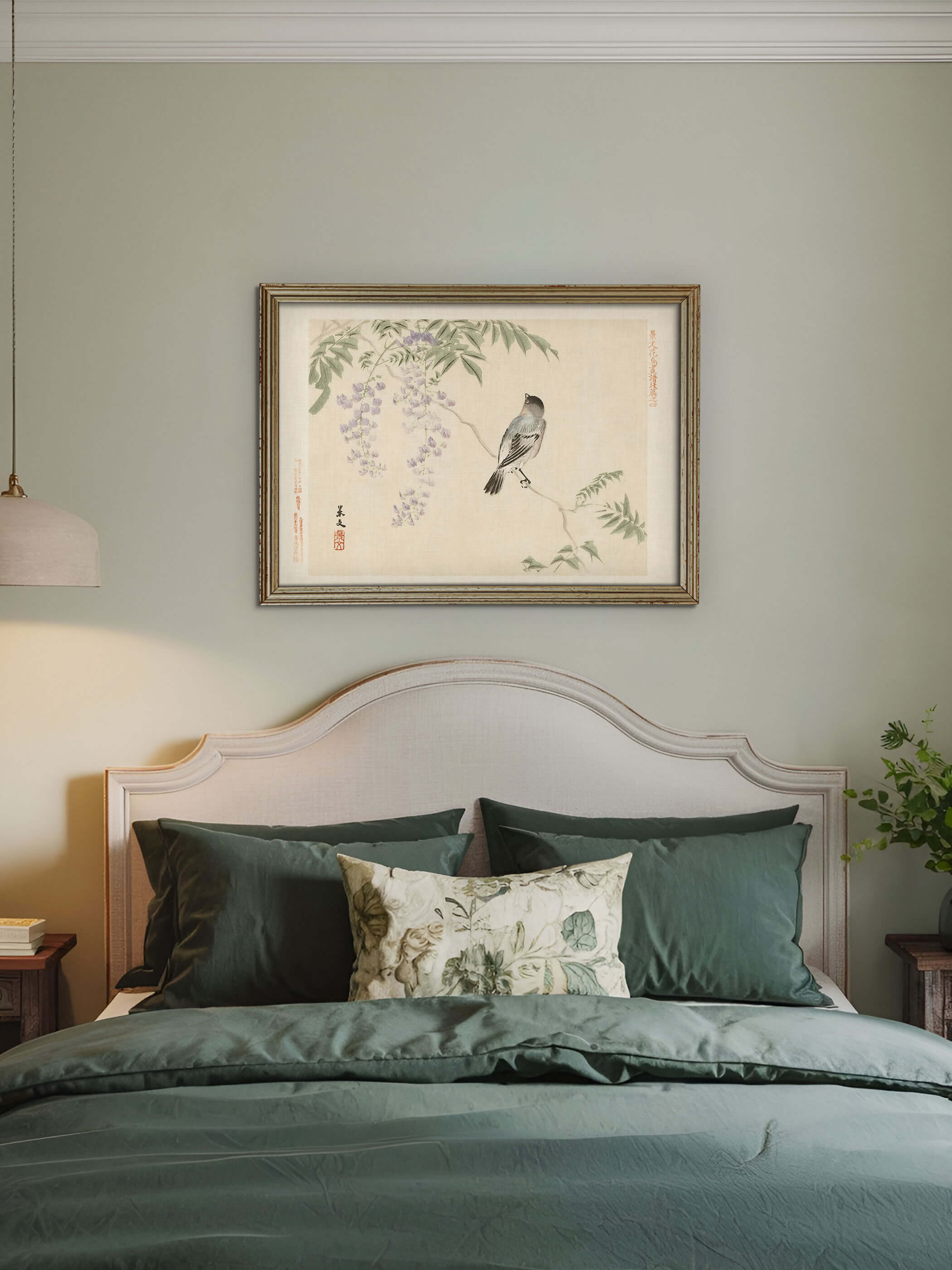Chinoiserie Wandbild mit Vogel im Blauregen hängt gerahmt über einem Bett mit salbeigrüner Bettwäsche vor gedeckter Wandfarbe. Der ruhige Kunstdruck bringt eine sanfte, elegante Stimmung ins Schlafzimmer.