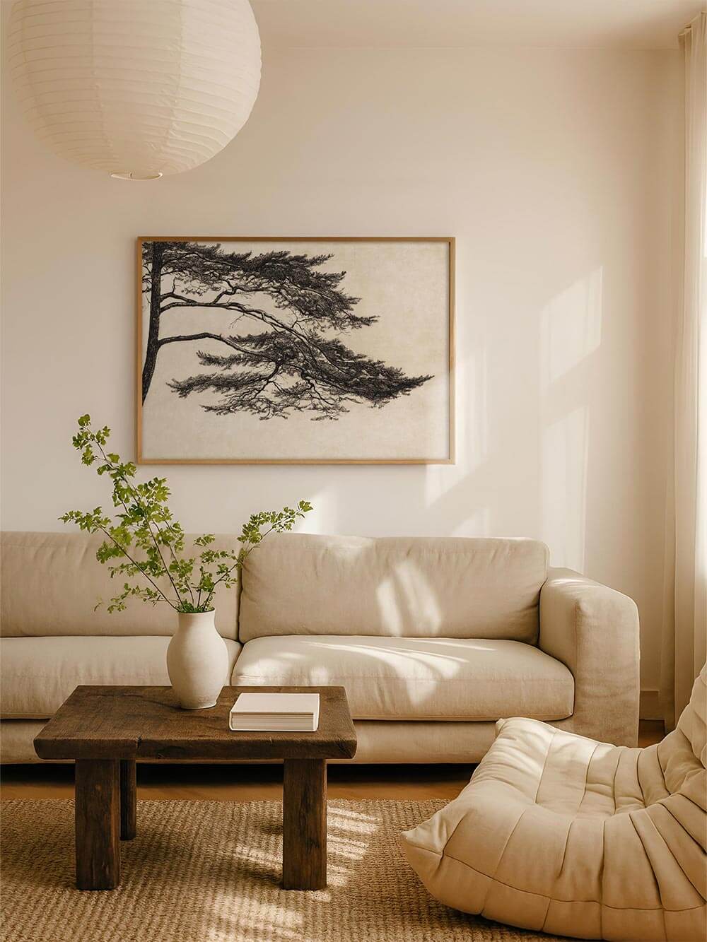 Japandi-inspirierter Kunstdruck mit filigraner Kiefer auf beigem Hintergrund über einem cremefarbenen Sofa. Das Wandbild bringt Ruhe und Harmonie in minimalistische Räume – perfekt für Wabi-Sabi oder Japandi Interiors.
