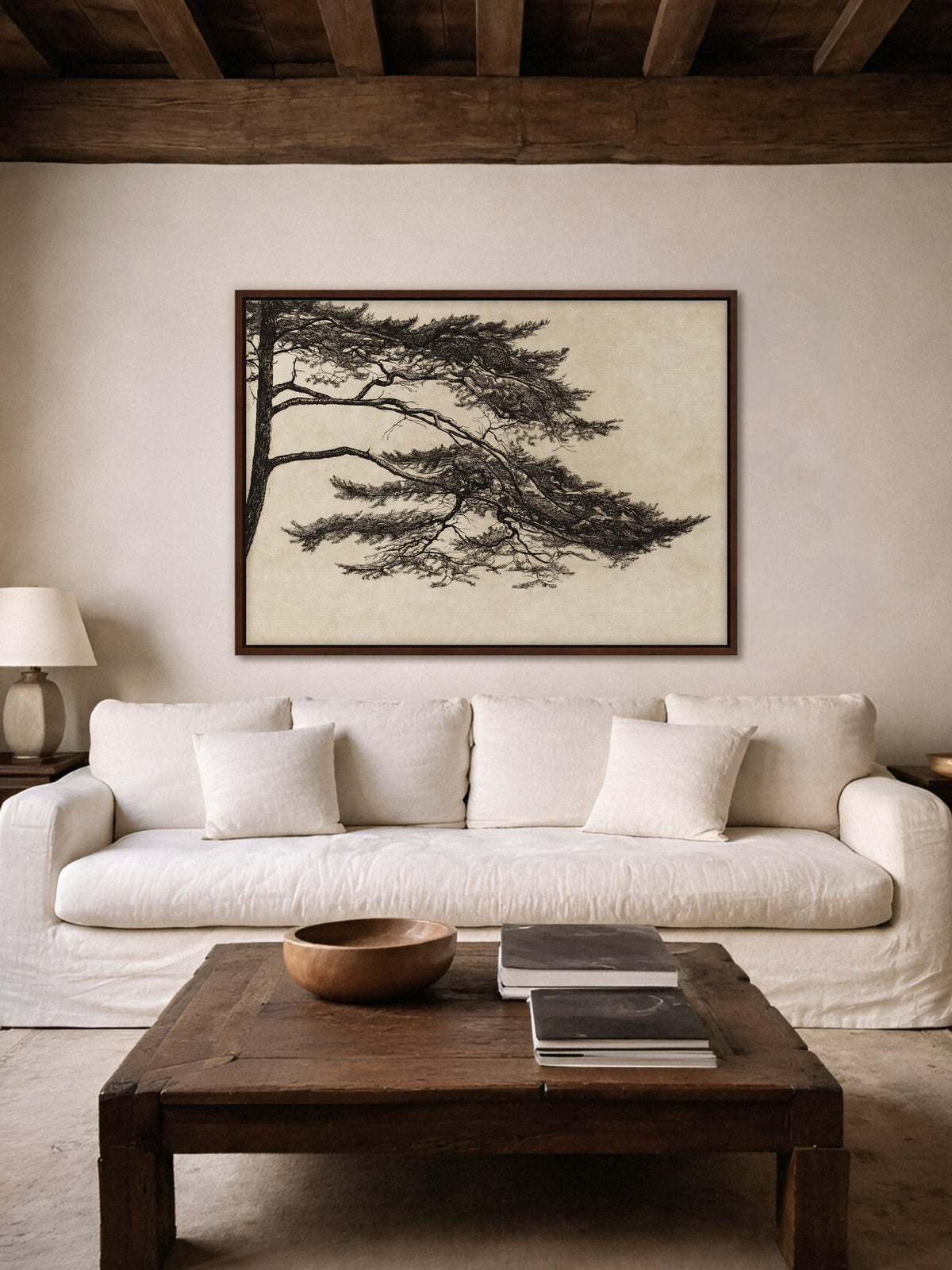 Leinwandbild mit detailreicher schwarzer Kiefer auf warmem Beigeton über einem weißen Sofa. Die monochrome Baumzeichnung und der dunkle Holzrahmen ergänzen das ruhige, naturverbundene Wohnzimmer im Wabi Sabi und Japandi Stil.