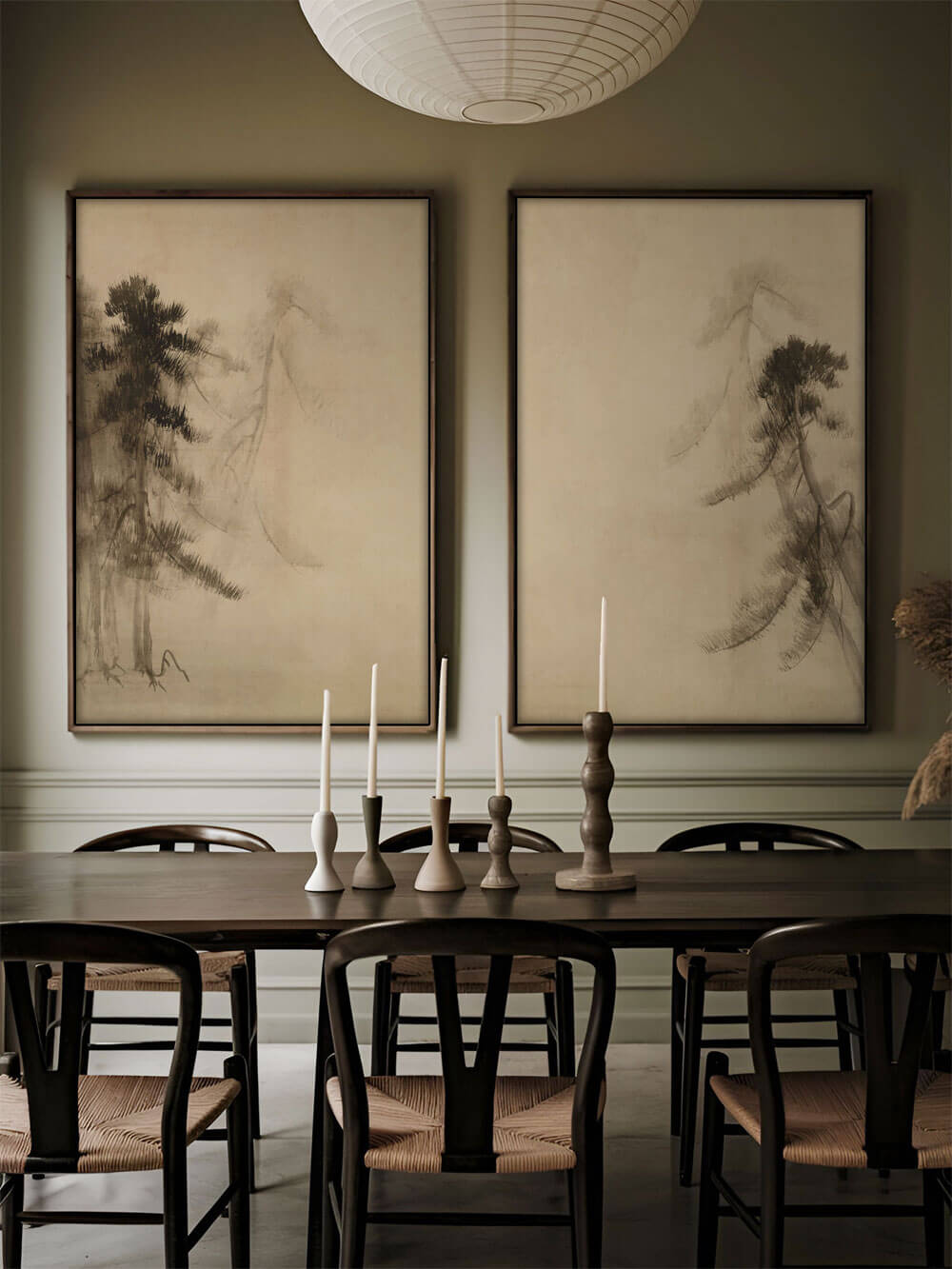 Zwei Wabi-Sabi-Kiefern-Skizzen-Kunstdrucke hängen über einem dunkelbraunen Esstisch, mit eleganten Kerzenhaltern und minimalistischer, japanisch inspirierter Einrichtung.
