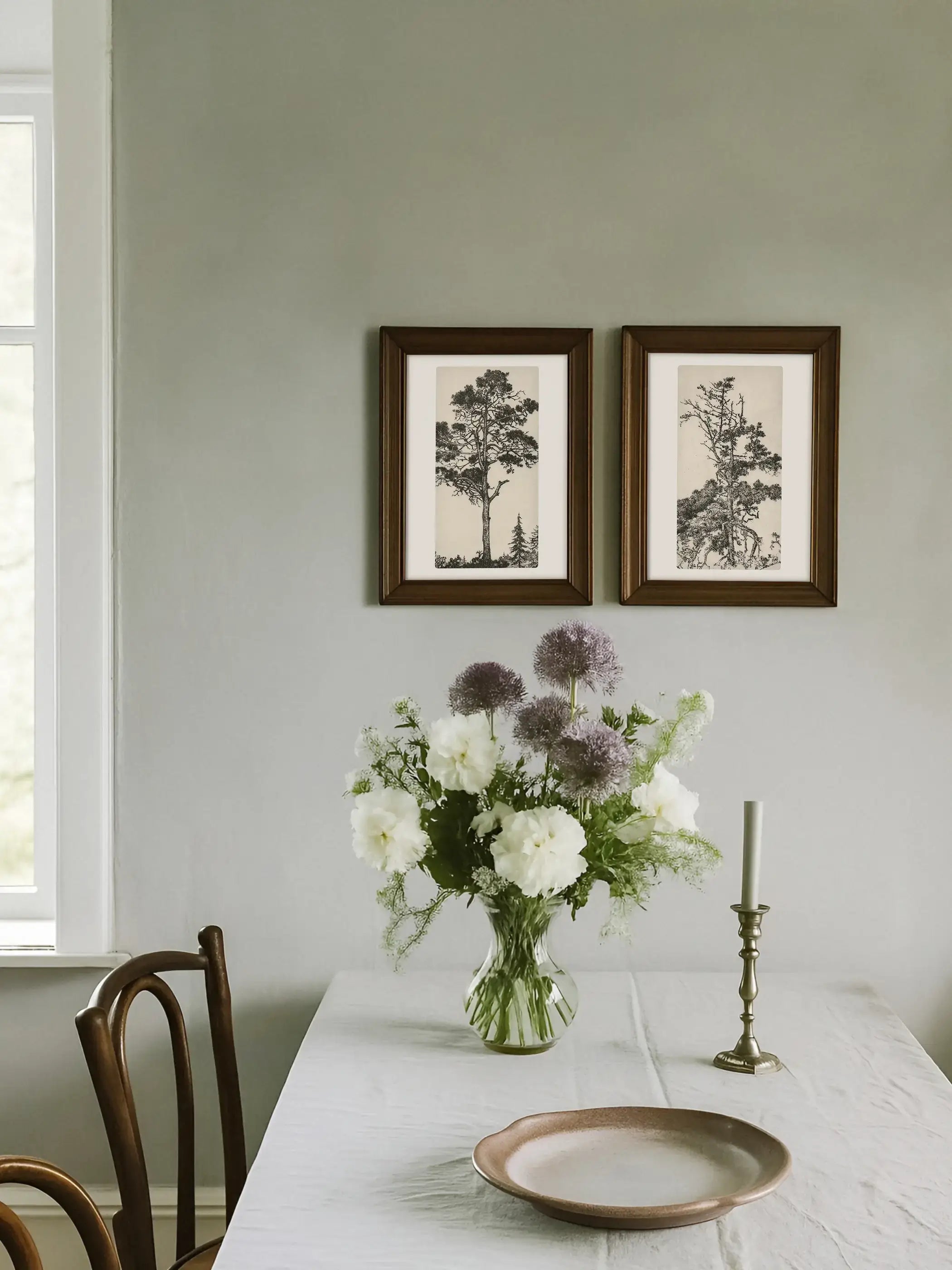 Zwei gerahmte Kieferzeichnungen hängen über einem Esstisch mit Blumenstrauß und schaffen eine ruhige Galerie-Wand. Die botanischen Kunstdrucke ergänzen Cottagecore, Landhausstil und zeitlose Naturdekoration.