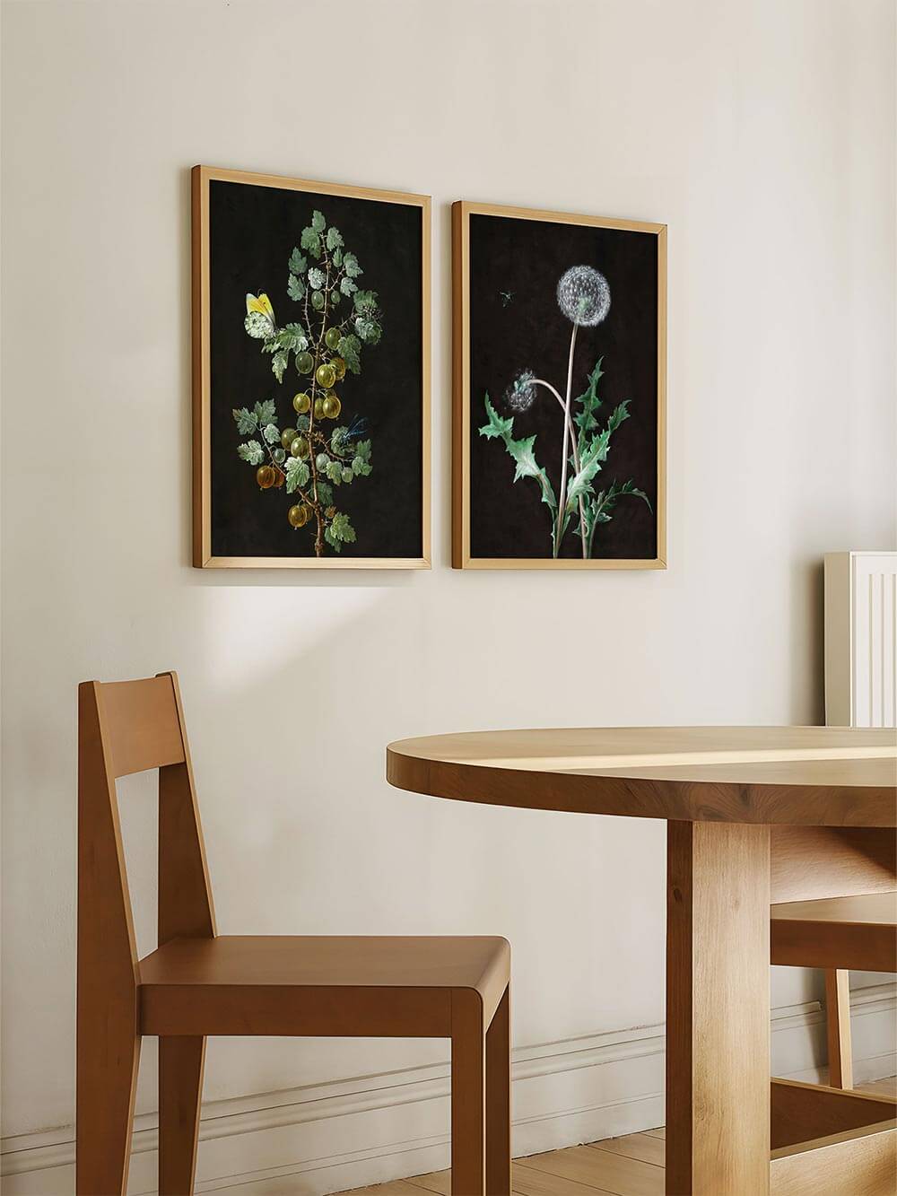 Zwei gerahmte botanische Kunstdrucke hängen nebeneinander an einer hellen Wand im Esszimmer. Das eine Motiv zeigt eine Stachelbeerranke, das andere eine Löwenzahnpflanze.