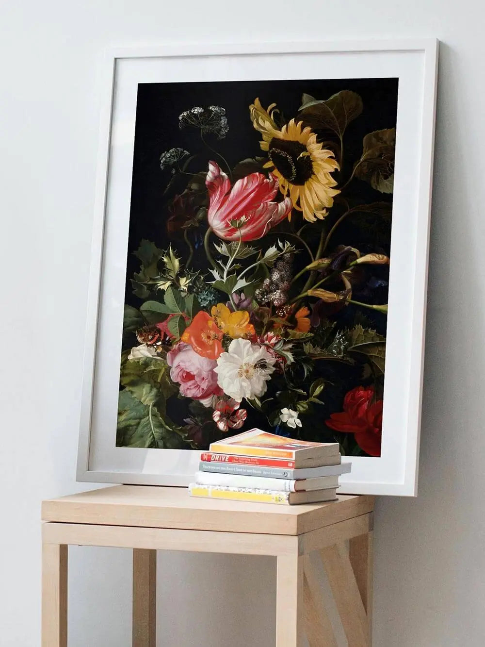 Gerahmter Blumen Kunstdruck im barocken Stil lehnt auf einem klienen Holztisch mit Büchern. Das detailreiche Stillleben mit Sonnenblume und Rosen setzt einen künstlerischen Akzent.