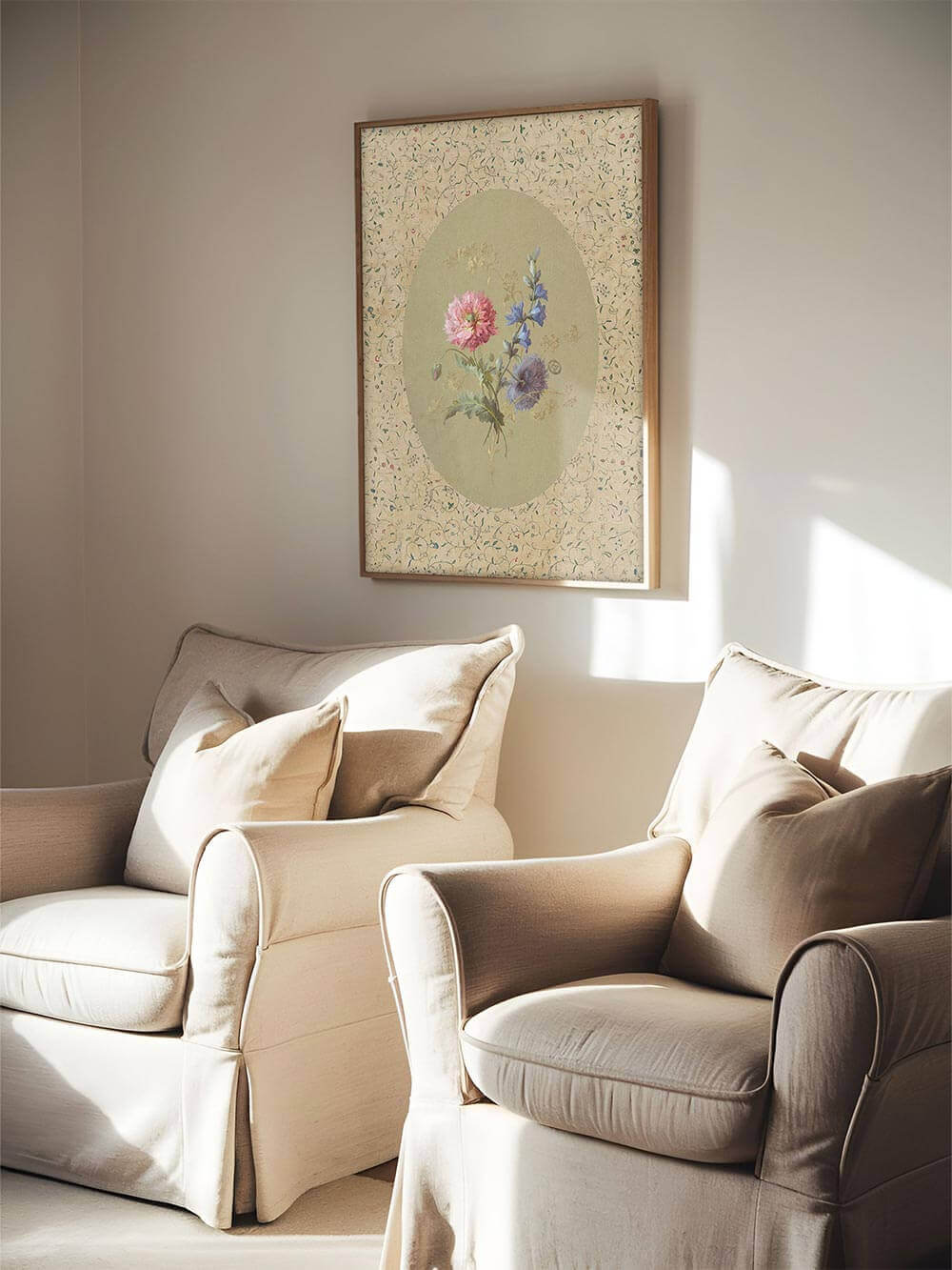 Der florale Kunstdruck in einem Holzrahmen hängt zwischen zwei beigen Sesseln in einem sanft beleuchteten Wohnzimmer, perfektes Statement für ruhige Cottage-Interieurs.