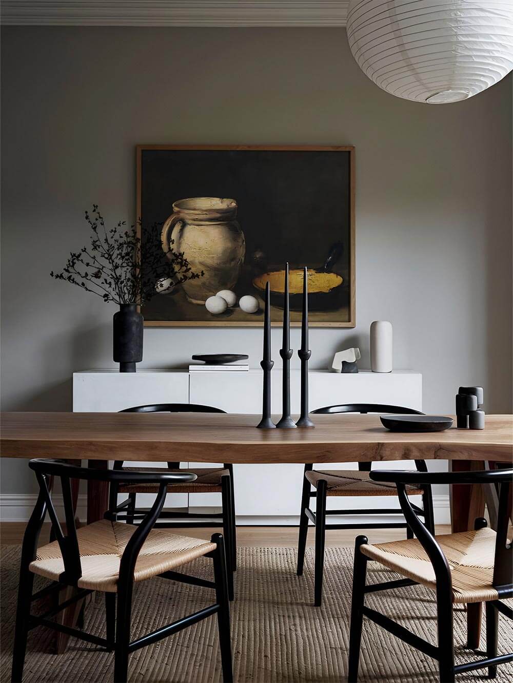 Rustikales Stillleben als Wandbild in einem modernen Esszimmer mit Holztisch und schwarzen Stühlen – harmonische Verbindung aus klassischer Kunst und zeitgenössischem Design.