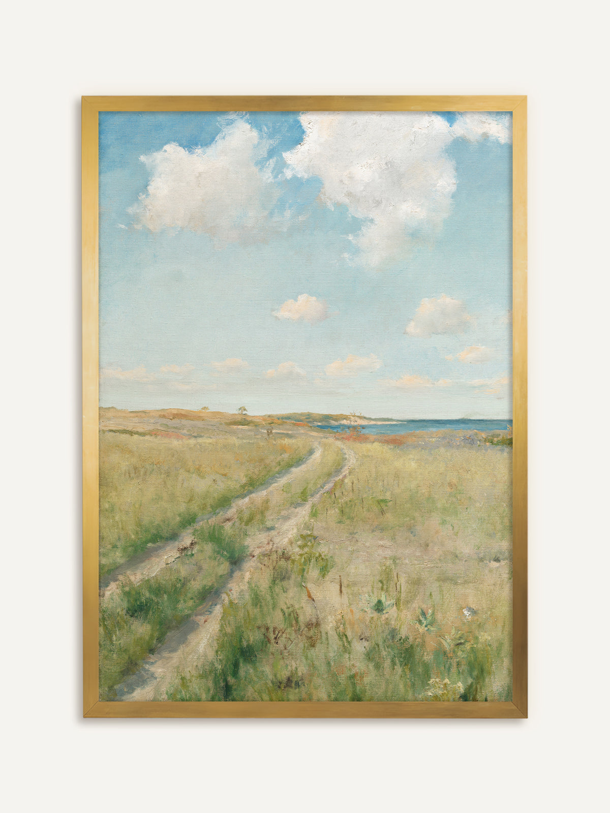 Wandbild, das einen sandigen Feldweg zeigt, der sich durch eine grüne Sommerwiese zum blauen Meer zieht, darüber große weiße Wolken an einem hellen Himmel. Der goldene Rahmen nimmt die sandigen Töne auf und gibt dem Bild einen Vintage Glanz. #Rahmen_Gold