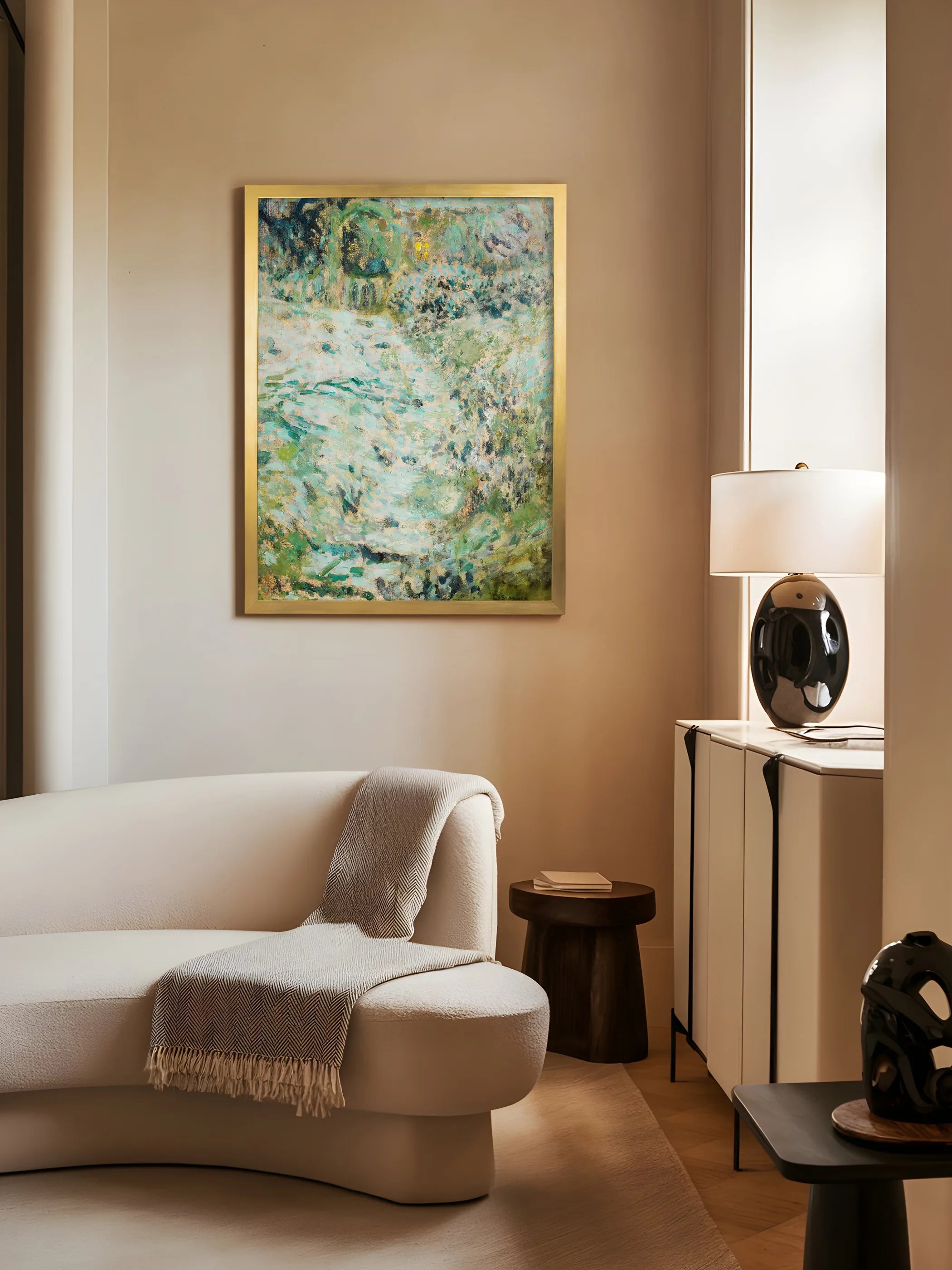 Landschafts-Kunstdruck in schmalem Goldrahmen hängt an beigefarbener Wand neben einem cremefarbenen Boucle-Sofa mit Wolldecke. Das türkisgrüne Wandbild setzt einen ruhigen Akzent in warmer Wohnzimmeratmosphäre.