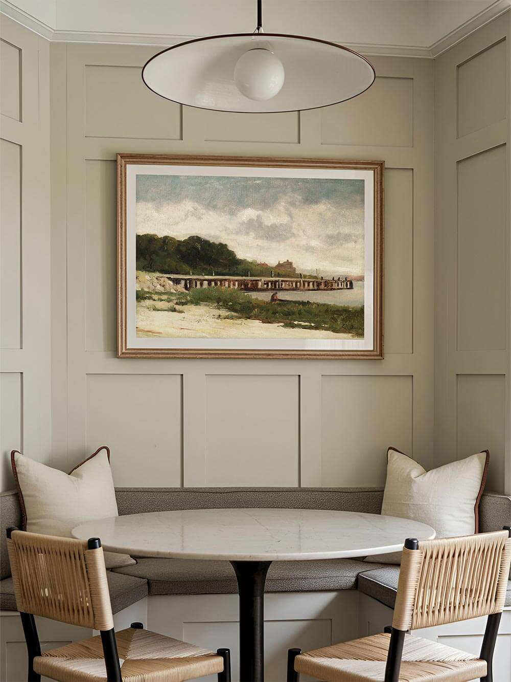 Gerahmter Kunstdruck einer Küstenlandschaft in einem eleganten Esszimmer mit klassischen Wandvertäfelungen. Die impressionistische Darstellung mit Holzbrücke, bewachsenem Ufer und weichem Himmel schafft eine ruhige, zeitlose Atmosphäre im Raum.