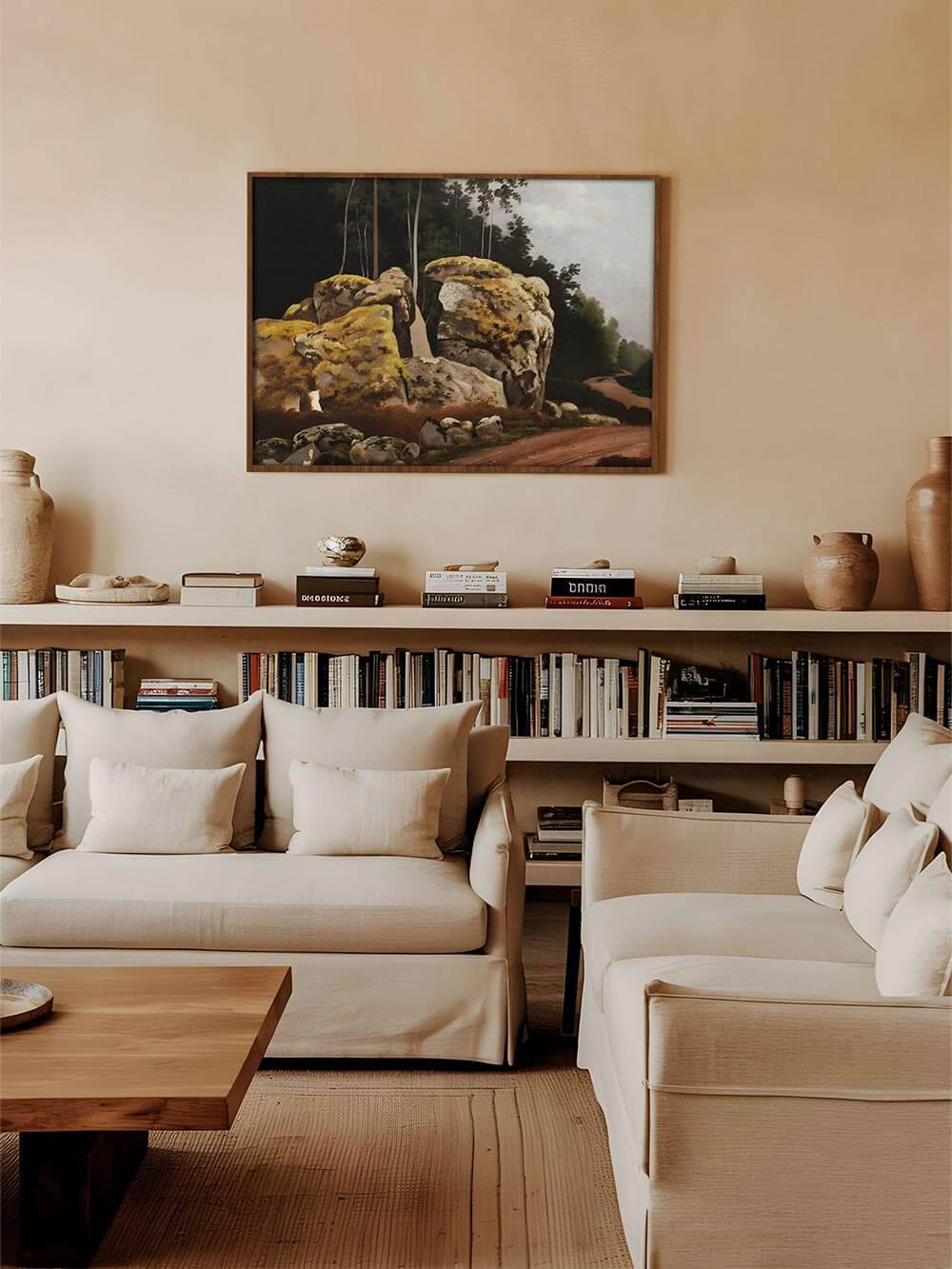 Stilvolles Wohnzimmer mit minimalistischem Design, in dem ein Landschaftsgemälde mit Felsen und Waldweg über einem Bücherregal hängt. Die warmen Erdtöne des Kunstdrucks harmonieren mit der neutralen Einrichtung.
