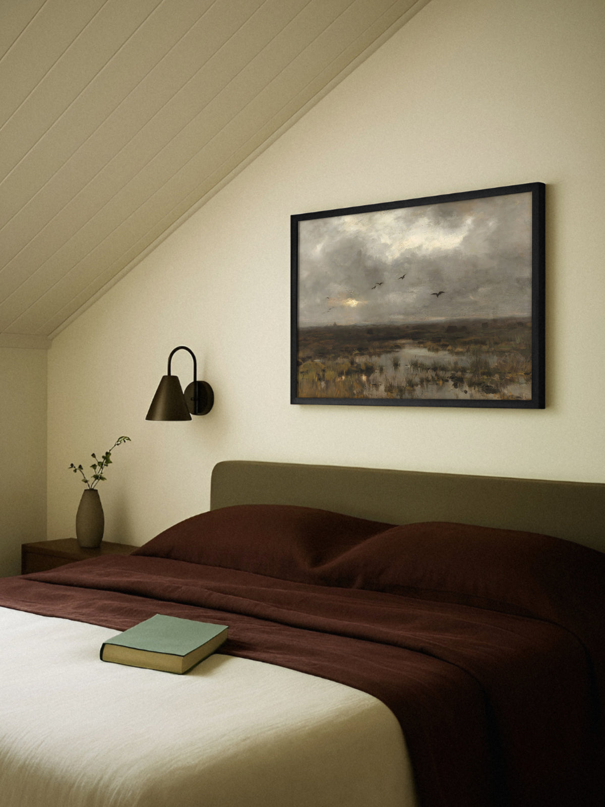 Moody Poster einer Moorlandschaft im schwarzen Rahmen über einem Bett mit olivgrünem Kopfteil und rotbrauner Leinenbettwäsche unter einer Dachschräge, daneben eine dunkle Wandleuchte.