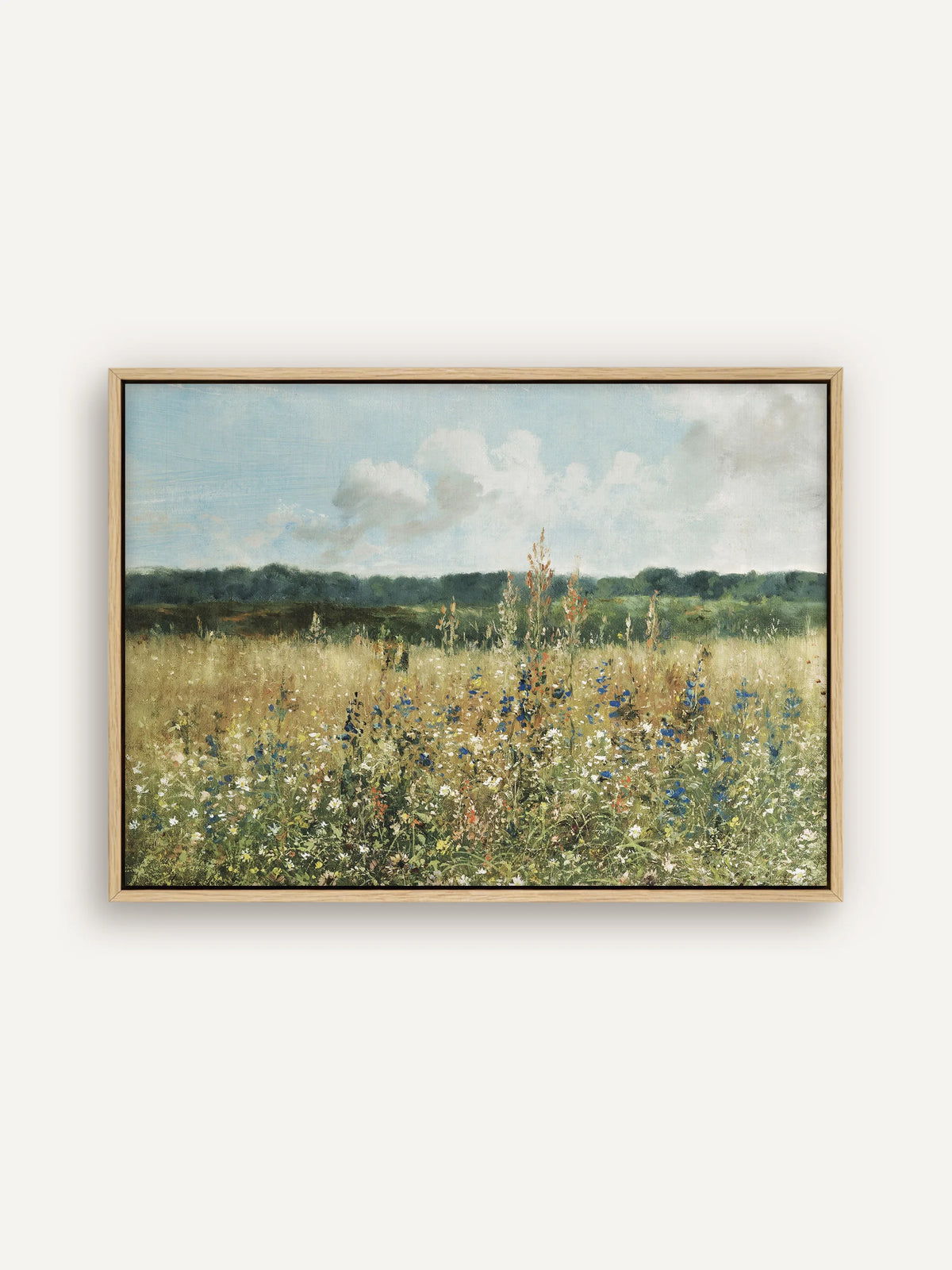 Cottagecore Leinwandbild im Querformat im naturfarbenen Schattenfugenrahmen. Eine Wiese mit blauen, weißen und roten Wildblumen im hohen Gras liegt vor einem dunkelgrünen Waldrand unter hellblauem Himmel. #Rahmen_Natur