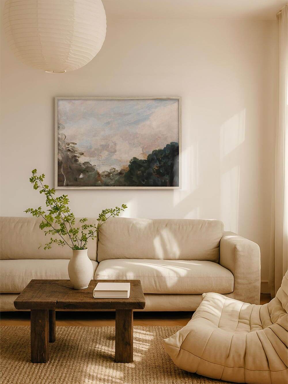 Heller Kunstdruck mit pastellfarbenem Himmel und weich angedeuteter Landschaft hängt über einem Sofa in einem ruhigen, lichtdurchfluteten Wohnzimmer. Das Wandbild erzeugt eine entspannte, zeitlose Stimmung und passt zu natürlicher, minimalistischer Wohnraumgestaltung.