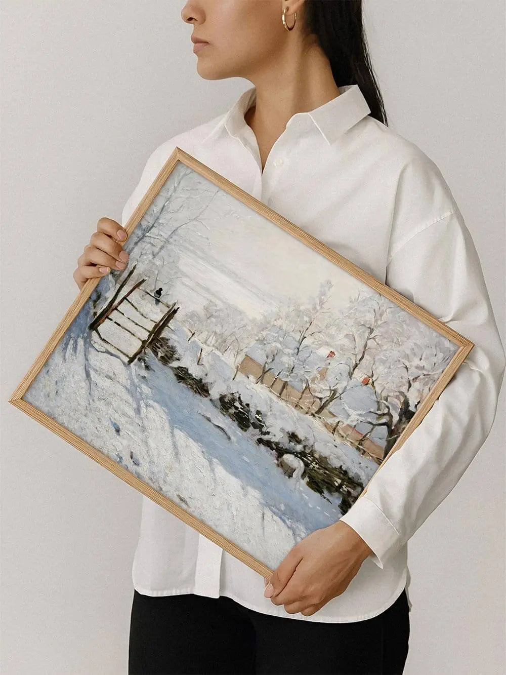 Eine Person hält den gerahmten Winterlandschaft Kunstdruck in den Händen, die verschneite Szene wirkt klar und poetisch.
