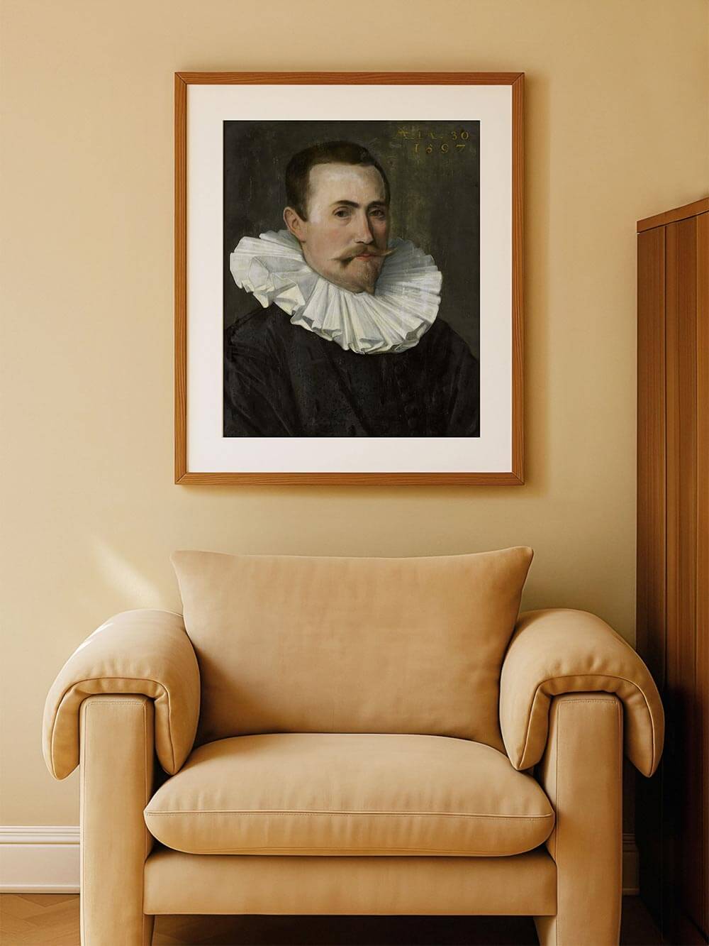 Gerahmter Kunstdruck eines Renaissance-Porträts mit charakteristischem Spitzenkragen. Der Druck hängt über einem beigefarbenen Sessel und verleiht dem Raum eine ruhige, historische Atmosphäre.