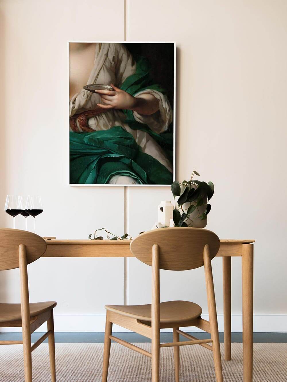 Barocker Kunstdruck mit smaragdgrünen Stoffen über einem Esstisch mit Weingläsern und hellen Holzstühlen. Das Wandbild bringt warme Eleganz und klassische Note in moderne Interiors.