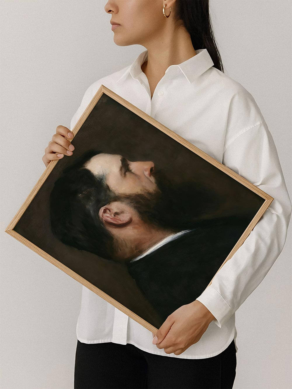 Frau hält einen Kunstdruck mit einem realistischen Männerporträt im Profil, dunkler Hintergrund und warme Farbnuancen. Perfekt für klassische oder moderne Wanddekoration mit Vintage-Flair.