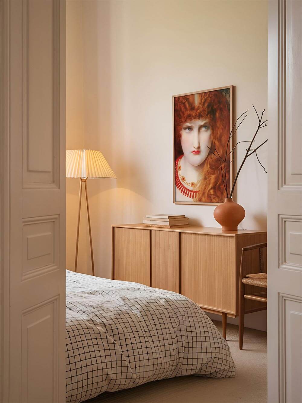 Der Vintage-Porträt-Kunstdruck hängt über einem hellen Sideboard im Schlafzimmer. Die tiefe Blickrichtung der Figur verleiht dem Raum eine geheimnisvolle Ruhe.