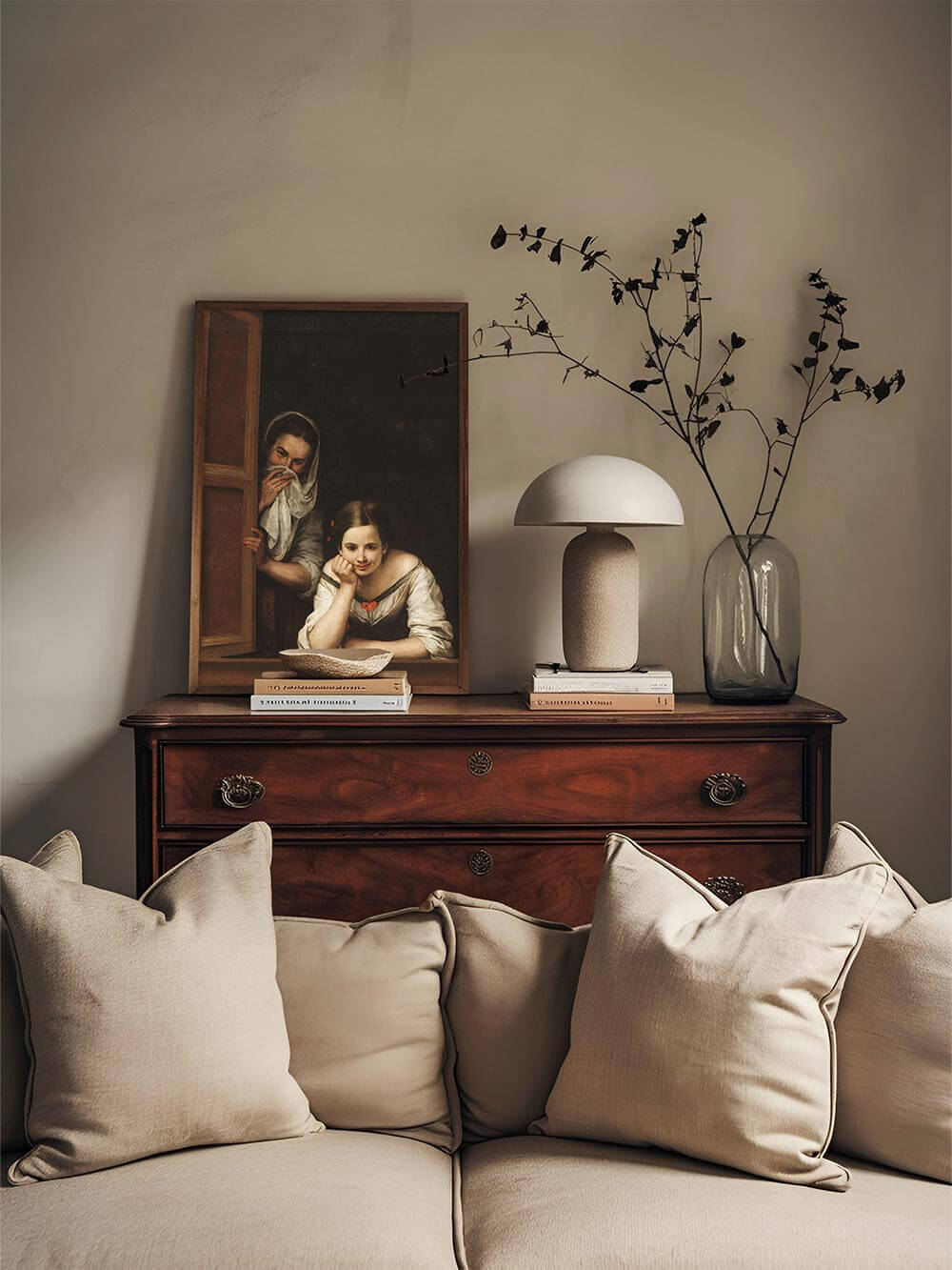 Gerahmt auf einer Holzkommode zwischen Keramik und Trockenblumen fügt sich der Kunstdruck stimmungsvoll ins ruhige Interieur ein. Die Szene wirkt vertraut und charmant.