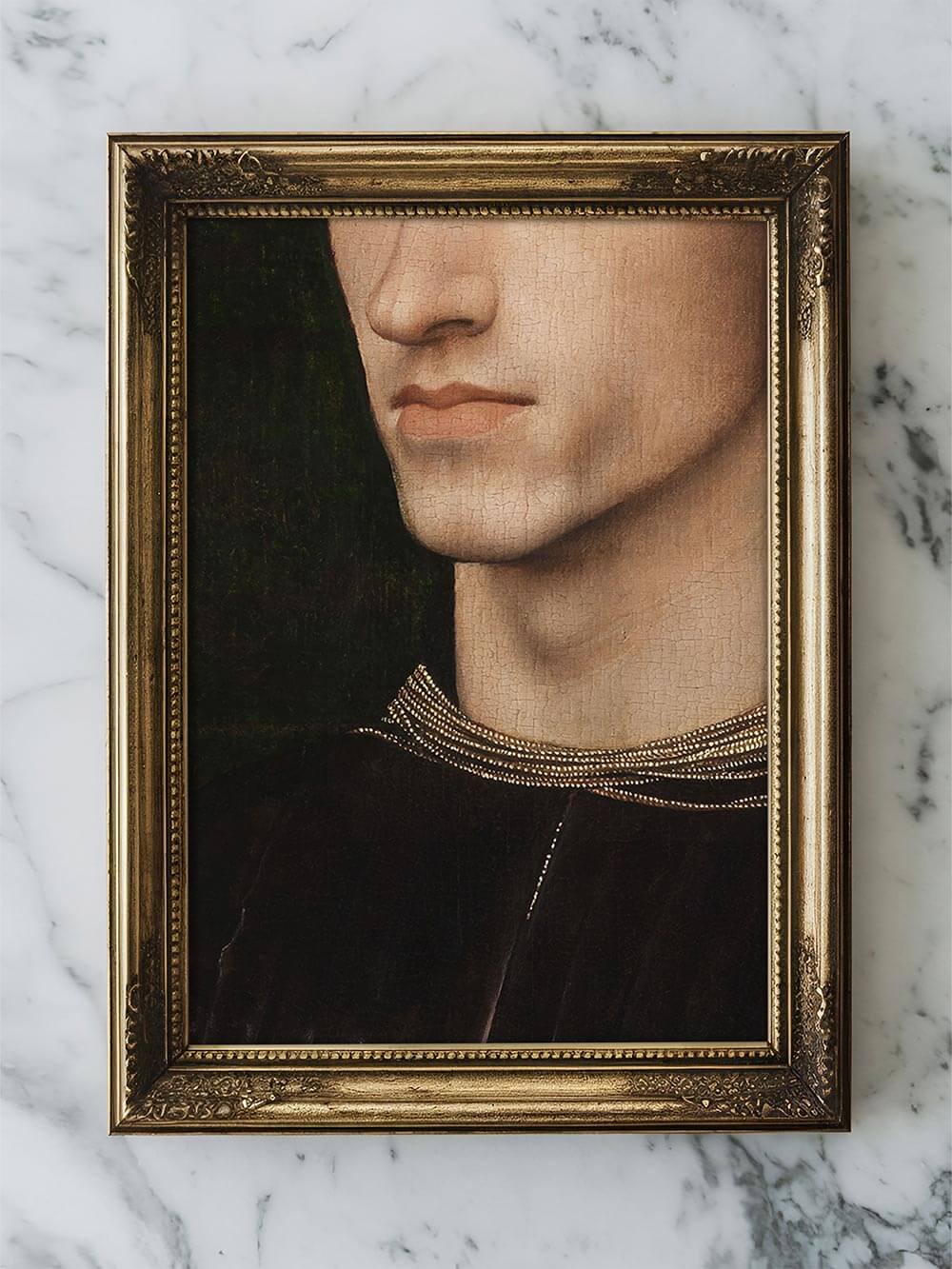Gerahmter Kunstdruck mit vergoldetem Rahmen liegt auf heller Marmoroberfläche. Antikes Porträt mit feinen Details und edlem Charakter, perfekt für elegante, kunstinspirierte Dekoration.