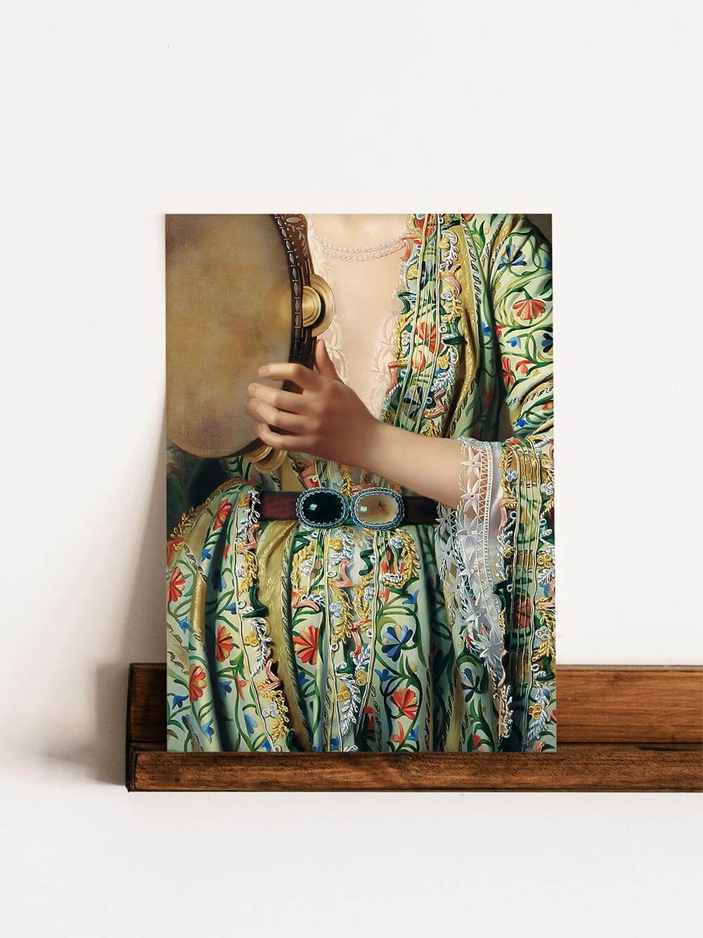 Detailaufnahme eines Kunstdrucks: Nahaufnahme eines Kunstdrucks mit einer reich bestickten, traditionellen Tracht in Gelb, Rot und Blau, mit filigranen Spitzenärmeln und einer auffälligen Gürtelschnalle.