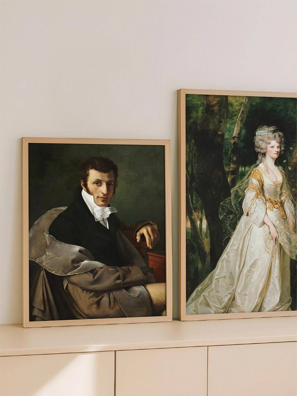 Der gerahmte Kunstdruck mit viktorianischem Männerporträt steht auf einem hellen Sideboard neben einem Damenporträt. Die klassische Darstellung bringt Ruhe in das moderne Interieur.