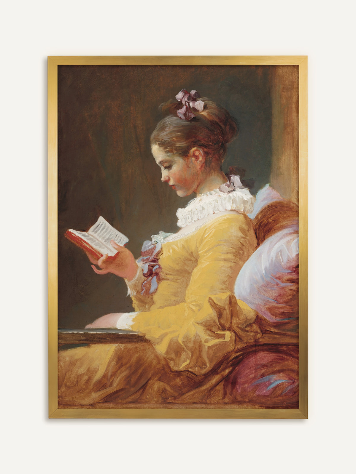 Wandbild, das eine junge Frau im Profil zeigt, im leuchtend gelben Kleid mit weißer Rüschenkrause und violetten Schleifen, die an ein rosa Kissen gelehnt in einem kleinen roten Buch liest, vor warmem braunem Grund. Im goldenen Rahmen leuchtet das Gelb des Kleides wie bei einem antiken Gemälde. #Rahmen_Gold