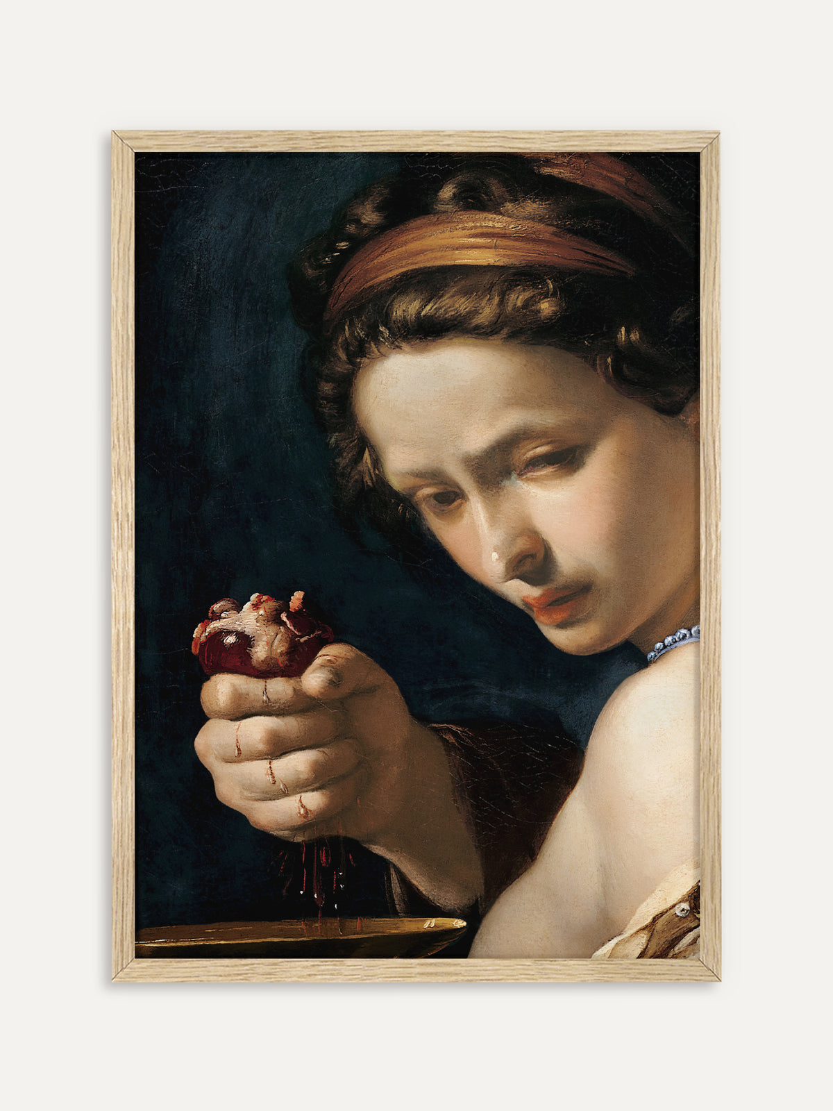 Kunstdruck, der eine Frau mit goldenem Haarband und Perlenkette zeigt, die vor dunkelblauem Hintergrund ein blutendes Herz über einer goldenen Schale hält. Der helle Holzrahmen setzt einen natürlichen Kontrast zum dramatischen Barockbild. #Rahmen_Helles Holz