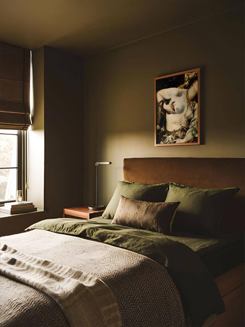 Das Vintage-Porträt mit sinnlicher Bildsprache hängt gerahmt über einem olivgrünen Bett und verleiht dem Schlafzimmer eine geheimnisvolle, opulente Atmosphäre.