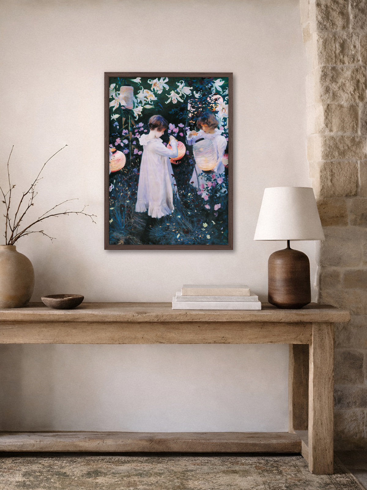 Viktorianisches Wandbild mit Mädchen zwischen Lilien und Rosen im dunklen Holzrahmen über einer rustikalen Konsole vor einer Steinwand, daneben eine Tischlampe.