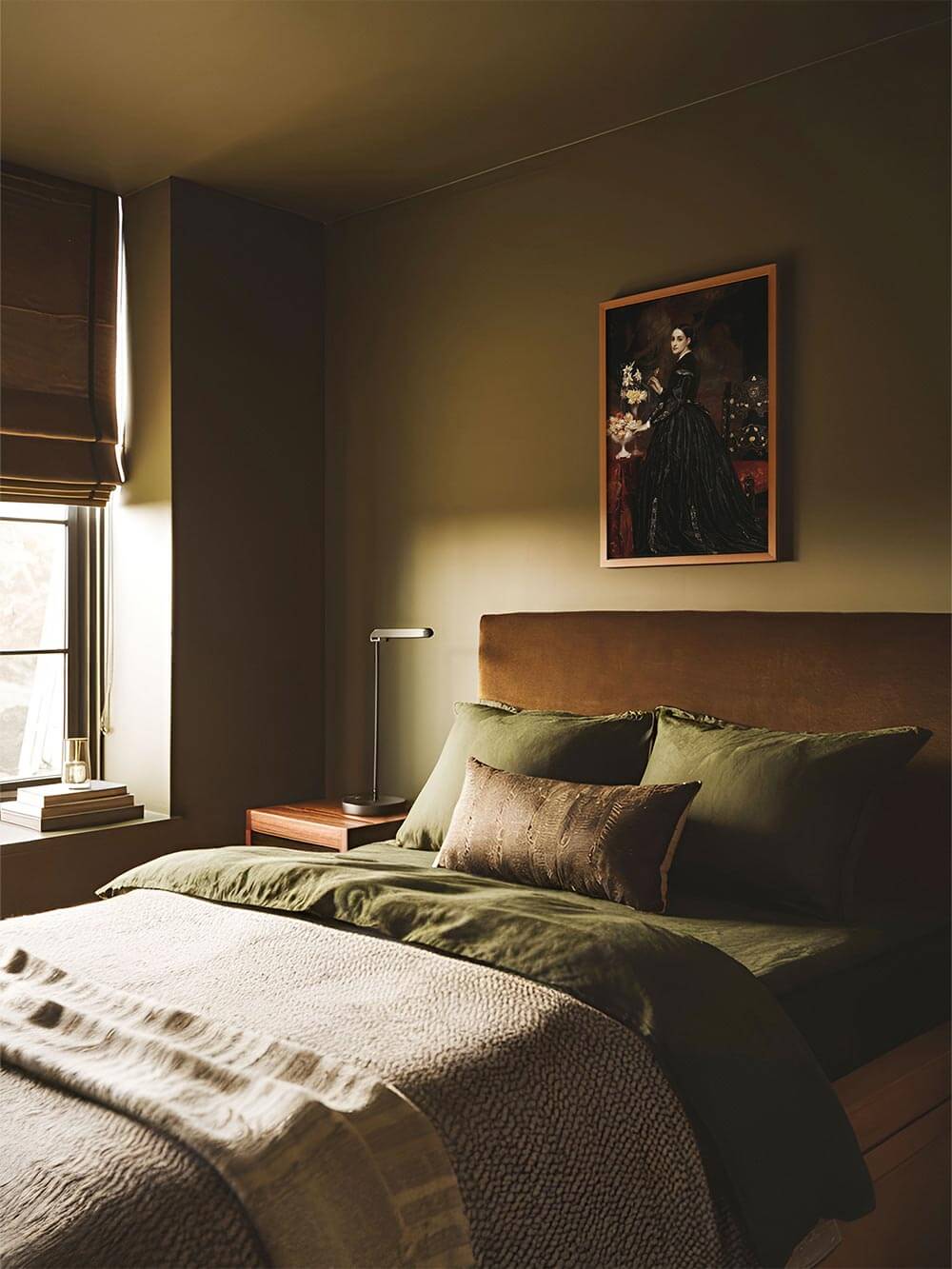 Der Vintage Kunstdruck hängt gerahmt über einem Bett mit olivgrüner Bettwäsche. Das viktorianische Porträt fügt sich harmonisch in das ruhige Interieur ein.