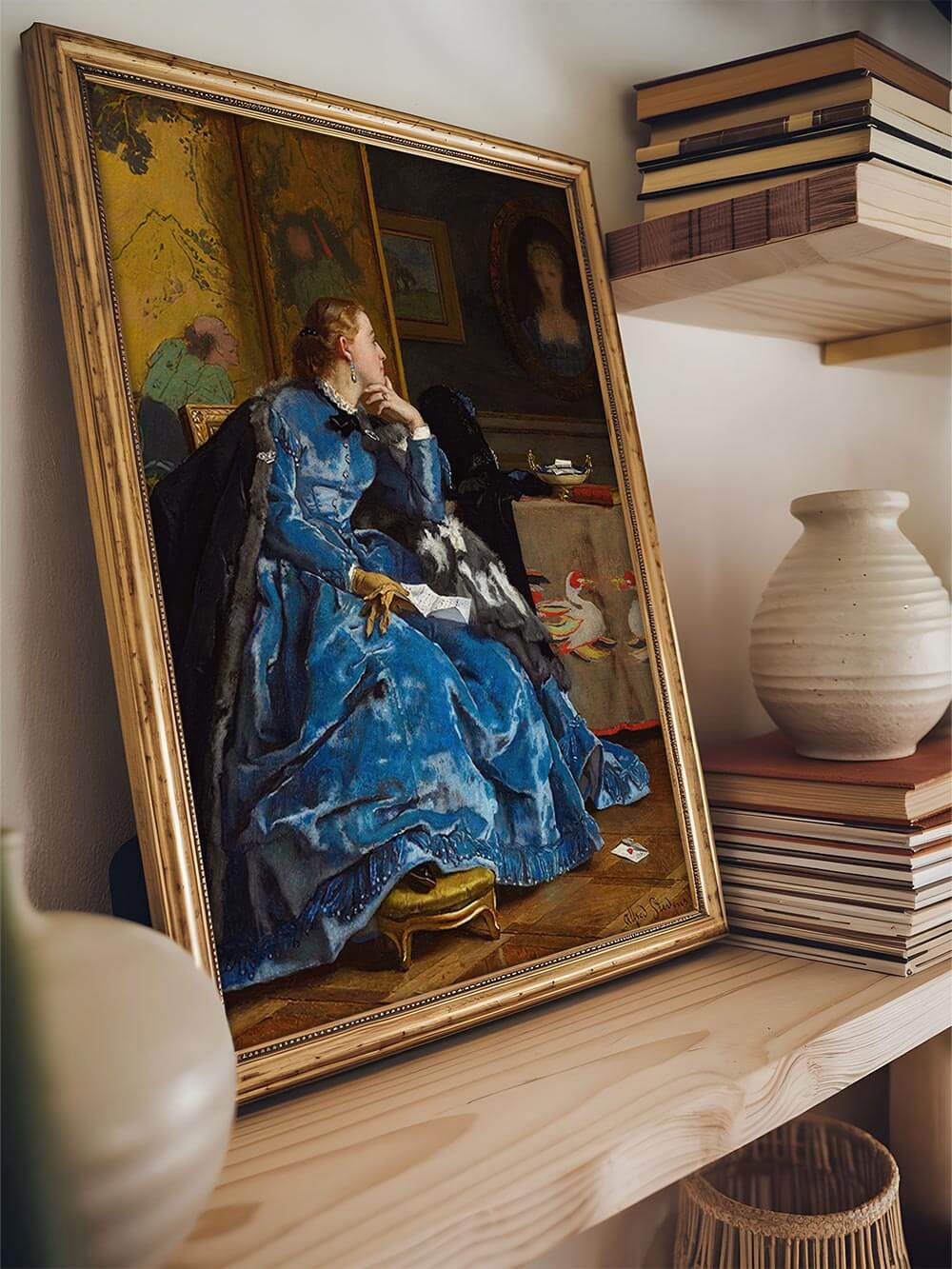 Kunstdruck im Goldrahmen zeigt viktorianische Frau in blauem Kleid, auf einem Holzregal zwischen Büchern und Keramikvasen platziert. Harmonische Wandkunst für klassische oder modern eingerichtete Interiors.
