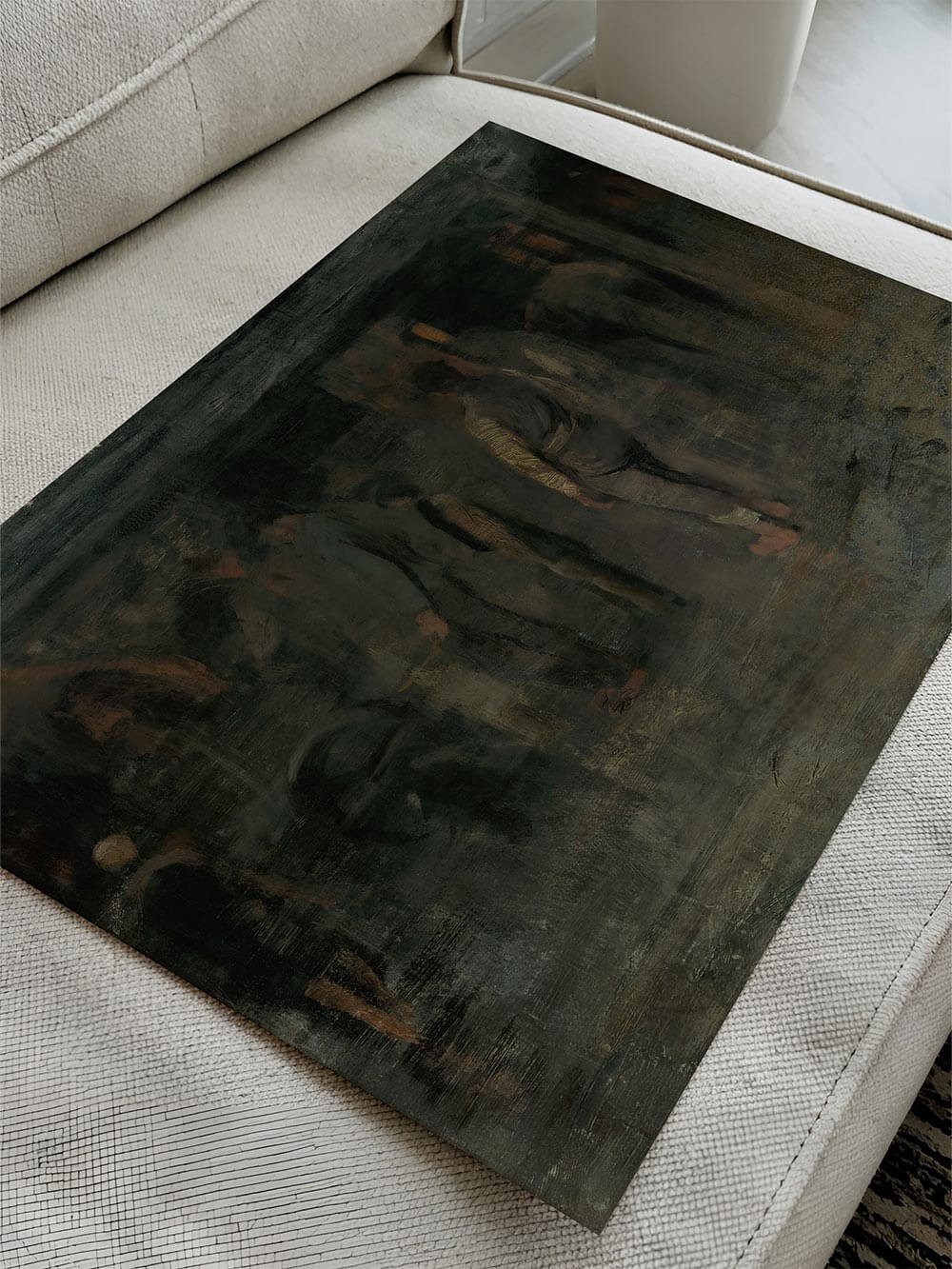 Der Kunstdruck liegt flach auf einem hellen Sofa und zeigt die matte Oberfläche sowie die dunkle, nuancierte Farbwirkung des Motivs. Die Aufnahme betont Materialität, Farbverlauf und die künstlerische Textur des Posters für eine realistische Produktdarstellung.