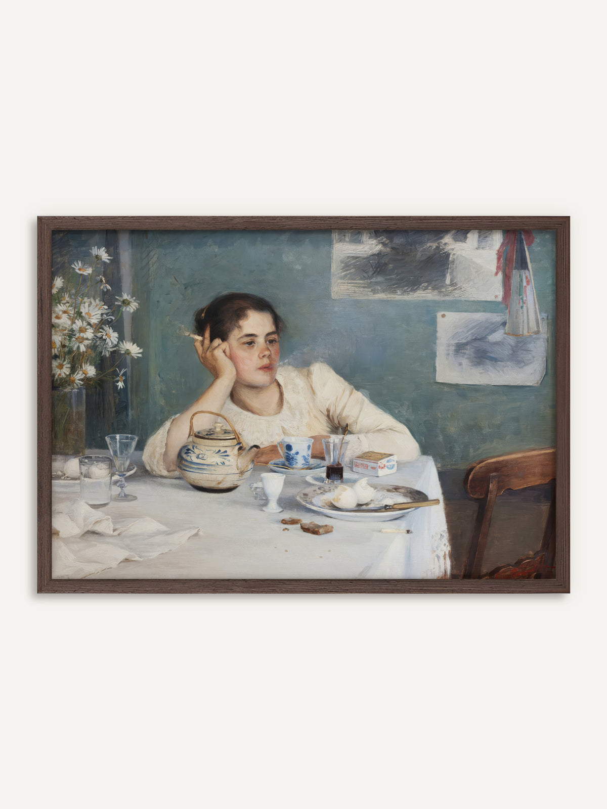 Poster, das eine junge Frau in weißer Bluse zeigt, die nach dem Frühstück mit einer Zigarette den Kopf in die Hand stützt, vor ihr ein Tisch mit blau-weißer Teekanne, Eierschalen und einem Strauß Margeriten vor blaugrüner Wand. Der Rahmen aus dunklem Holz gibt dem Vintage-Interieur einen warmen Halt. #Rahmen_Dunkles Holz