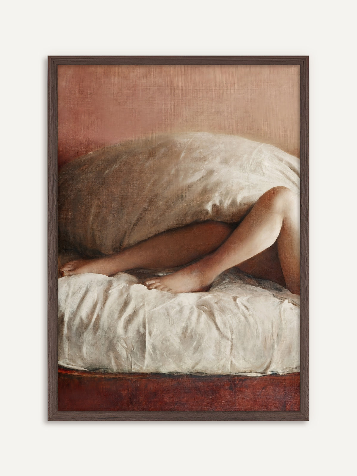 Wandbild, das die nackten Beine einer liegenden Frau zeigt, die unter einem großen hellen Kissen hervorragen und vor einer roséfarbenen Wand auf einem zerknitterten weißen Laken ruhen. Der Rahmen aus dunklem Holz nimmt das Rotbraun des Bettes auf und gibt dem Vintage-Poster Halt. #Rahmen_Dunkles Holz