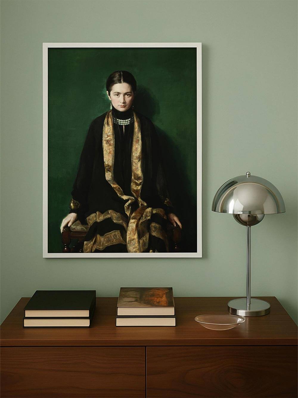 Kunstdruck eines historischen Porträts an mintgrüner Wand über moderner Kommode – die satte Farbpalette aus Schwarz, Gold und Smaragdgrün erzeugt eine stilvolle Raumwirkung.