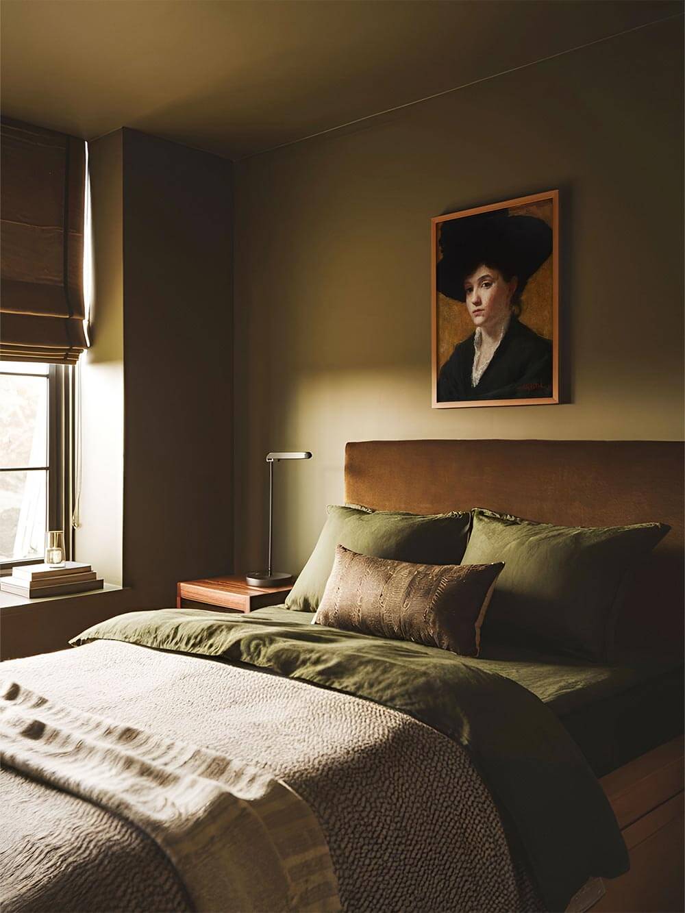 Der Kunstdruck mit Damenporträt hängt über einem moosgrünen Bett in einem ruhigen, stimmungsvoll eingerichteten Schlafzimmer. Das Bild ergänzt das harmonische Farbkonzept.