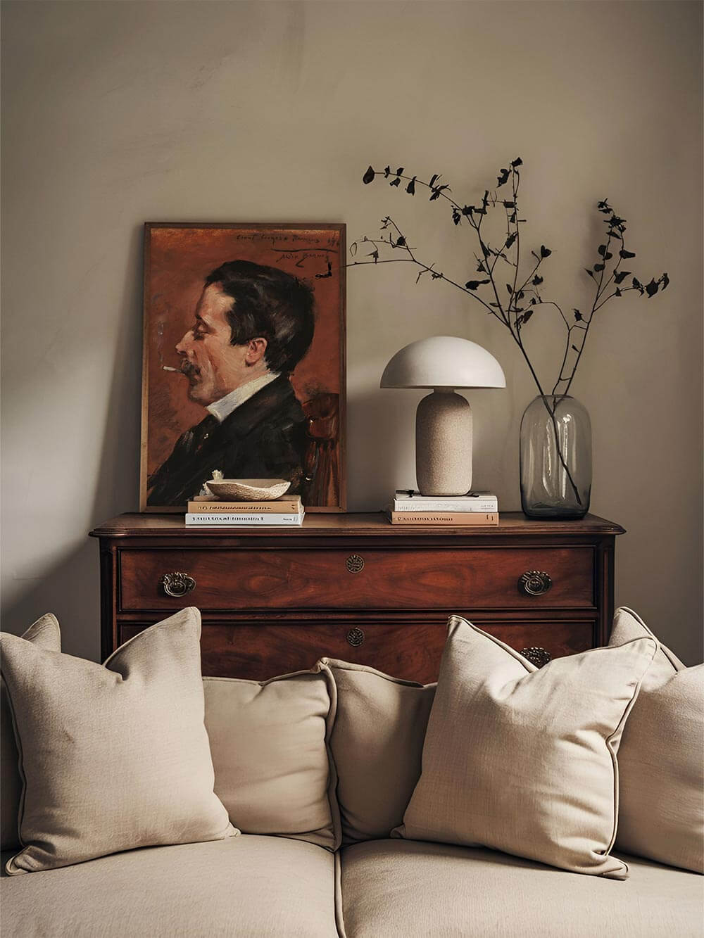 Klassischer Kunstdruck eines rauchenden Mannes im Profil auf Kommode über beigem Sofa. Der warme Braunton und die nostalgische Atmosphäre passen perfekt zu Moody- oder Dark-Academia-Interiors.