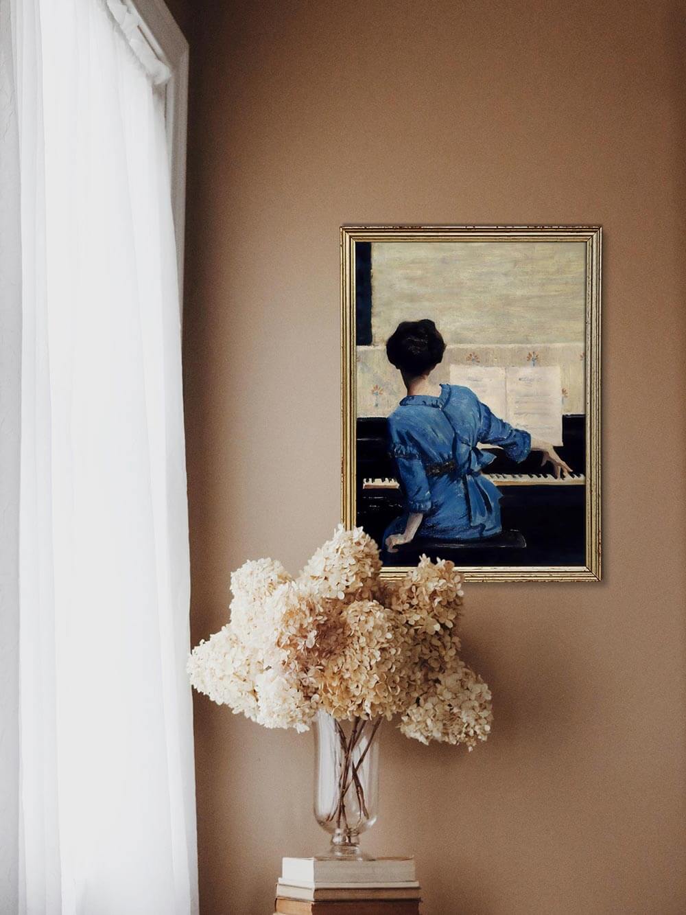Frauenporträt am Klavier in goldenem Rahmen über einem Tisch mit getrockneten Blumen. Nostalgisches Wandbild, das klassische Kunst mit moderner Raumdekoration verbindet.