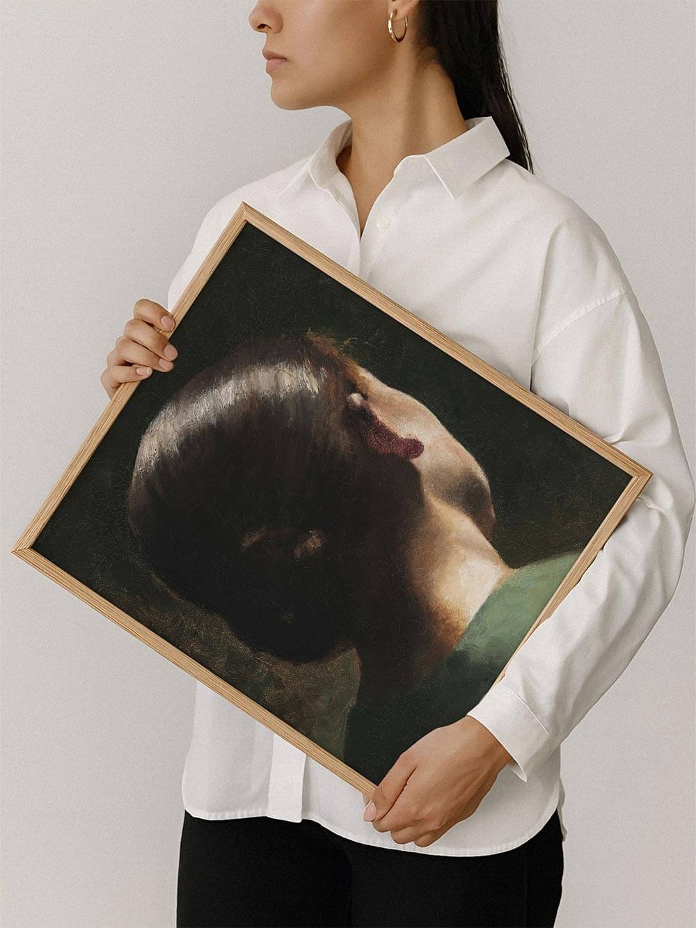 Frau hält einen Kunstdruck mit klassischem Porträt einer Frau von hinten, dunkle Farbpalette und feine Lichtreflexe auf Haar und Nacken. Perfekt als Wandbild im Vintage- oder Dark Academia-Stil.