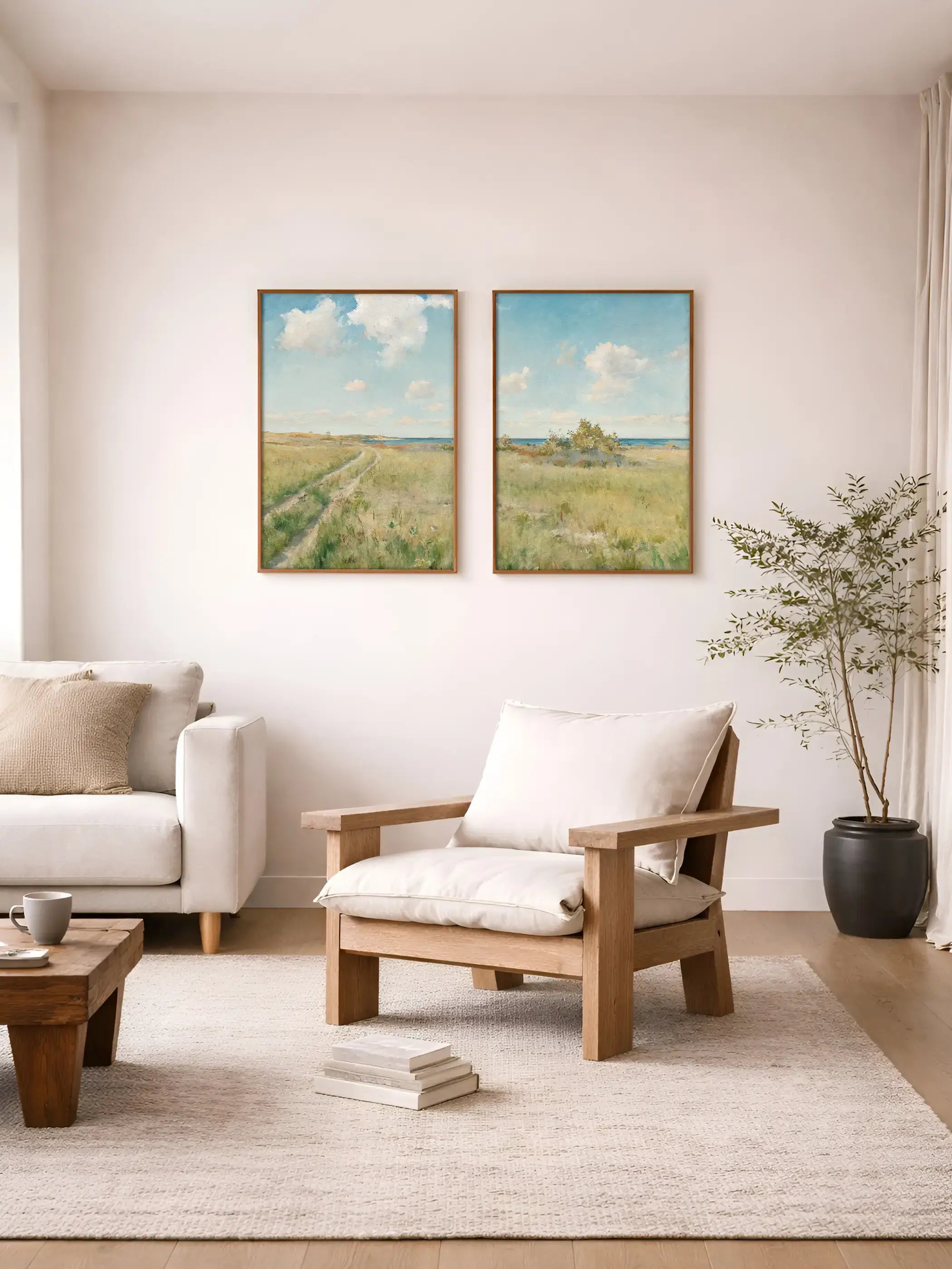 Zwei impressionistische Landschaftsbilder mit weitem Feld, Meerblick und Wolkenhimmel hängen über einem Sessel im Wohnzimmer.